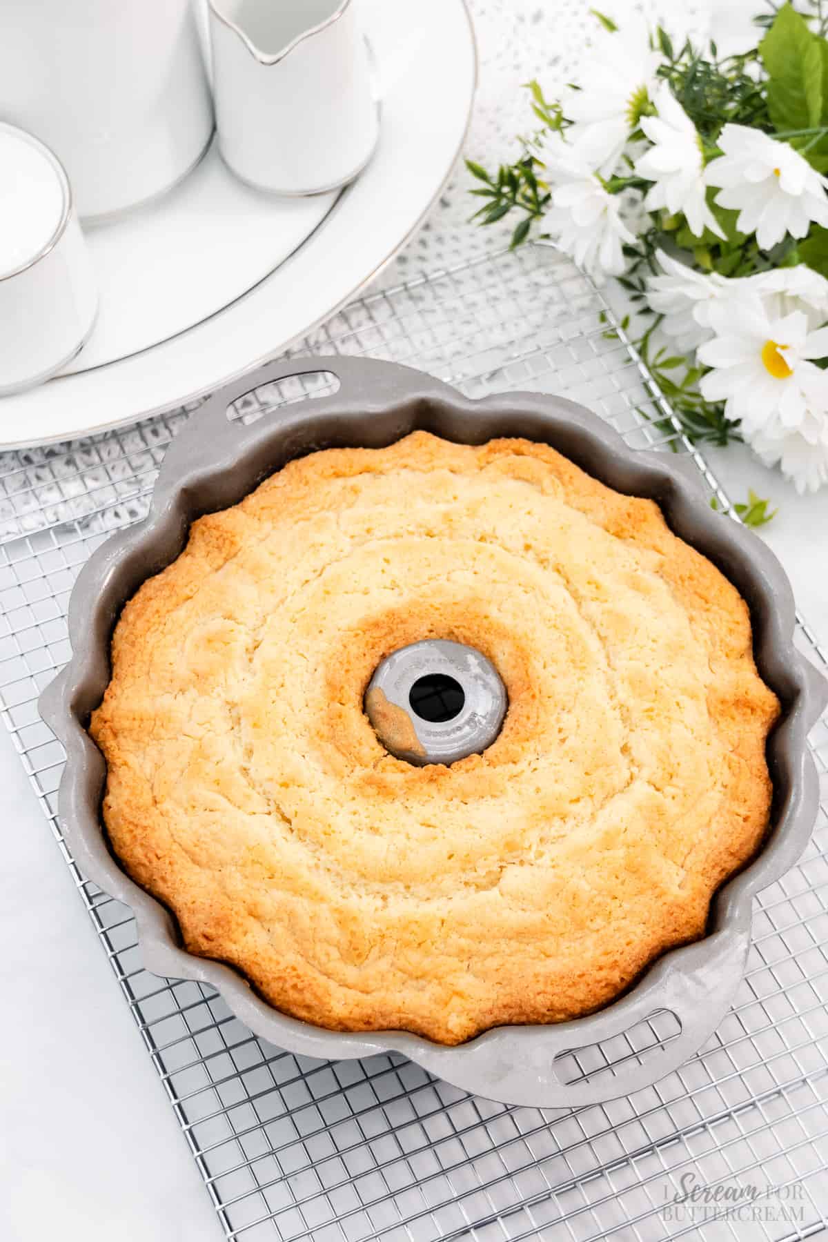 Baked pound cake in a bundt pan on a cooling rack.