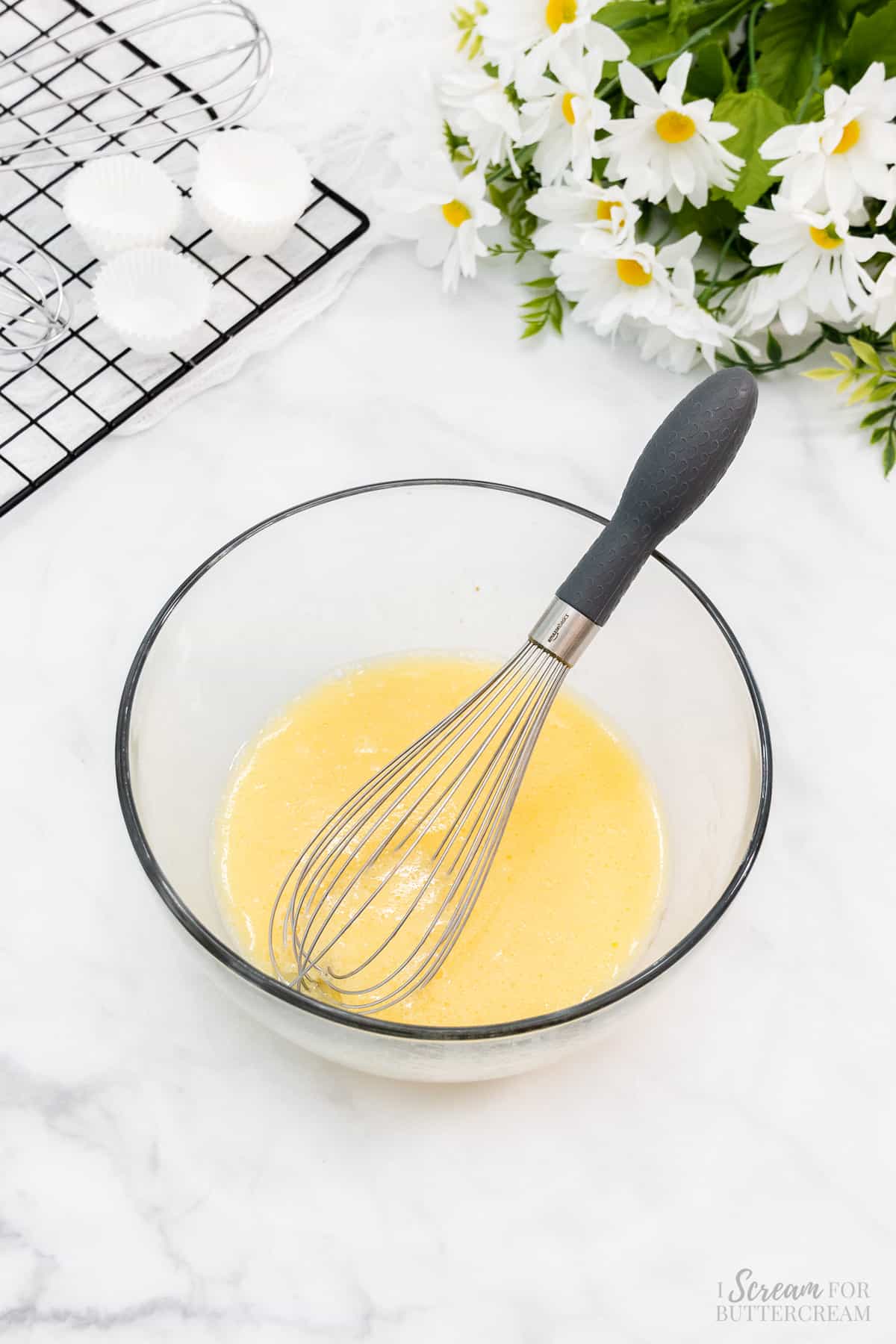Liquid ingredients in a glass bowl with a whisk.