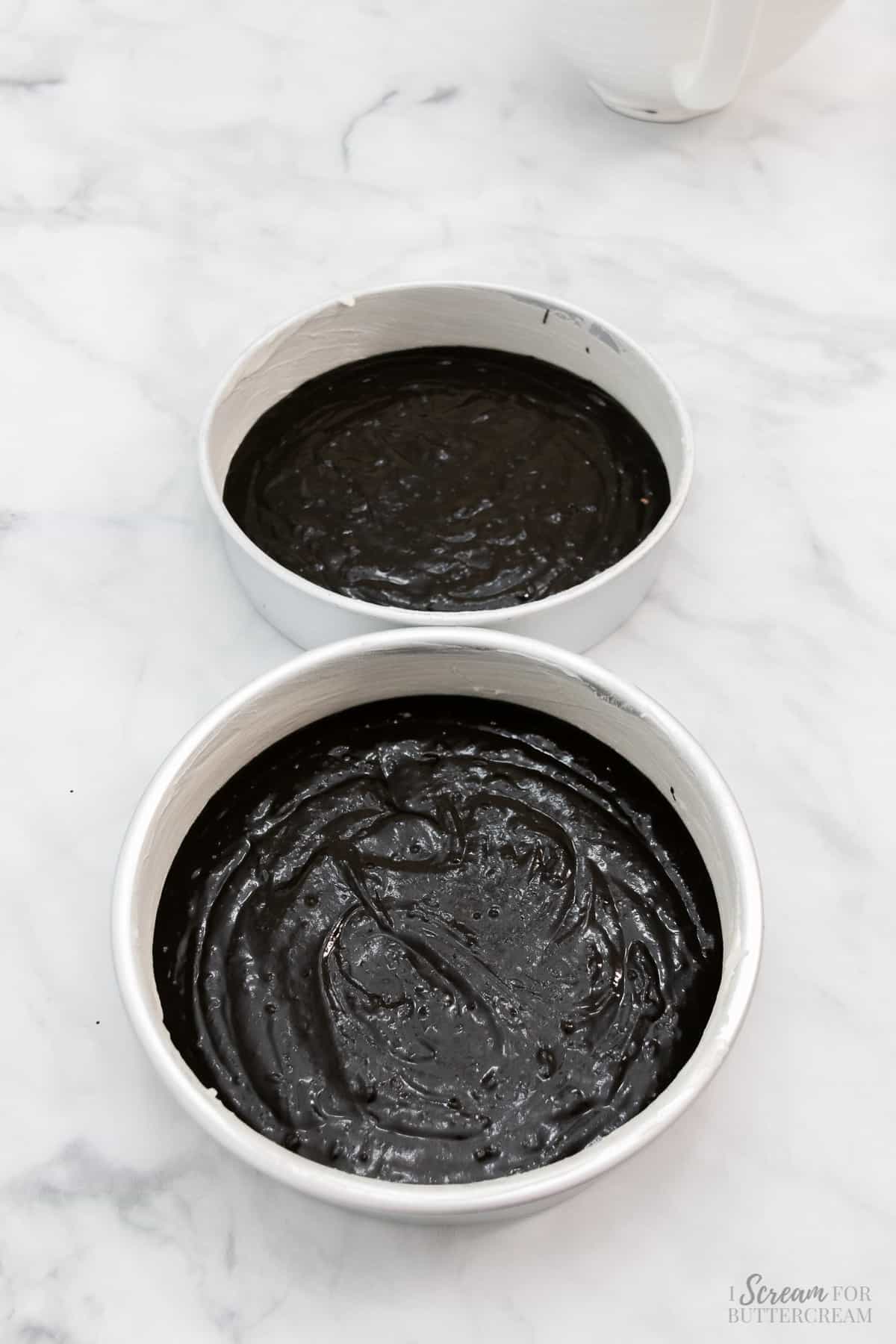 Black velvet cake batter poured into two pans.
