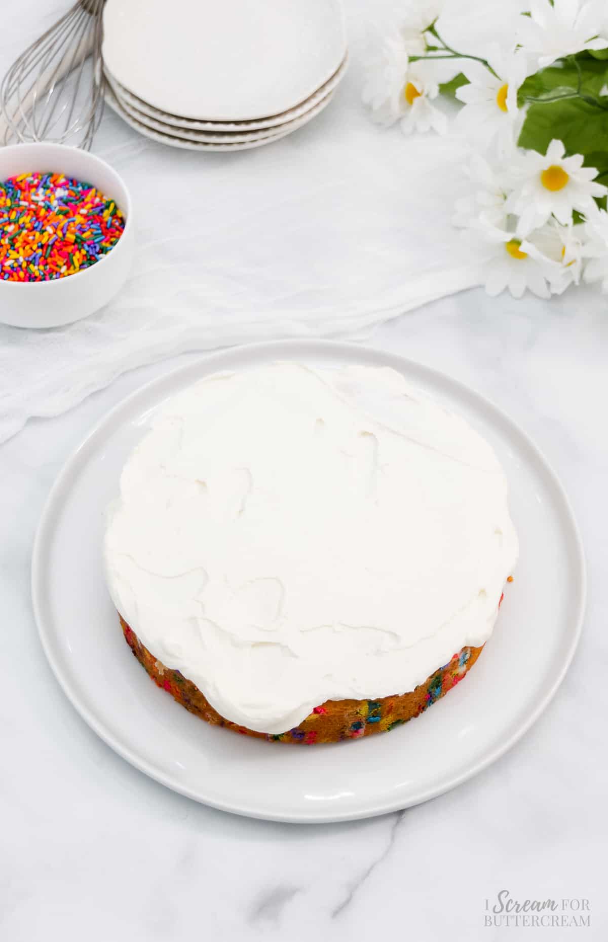Sprinkle cake layer with buttercream.