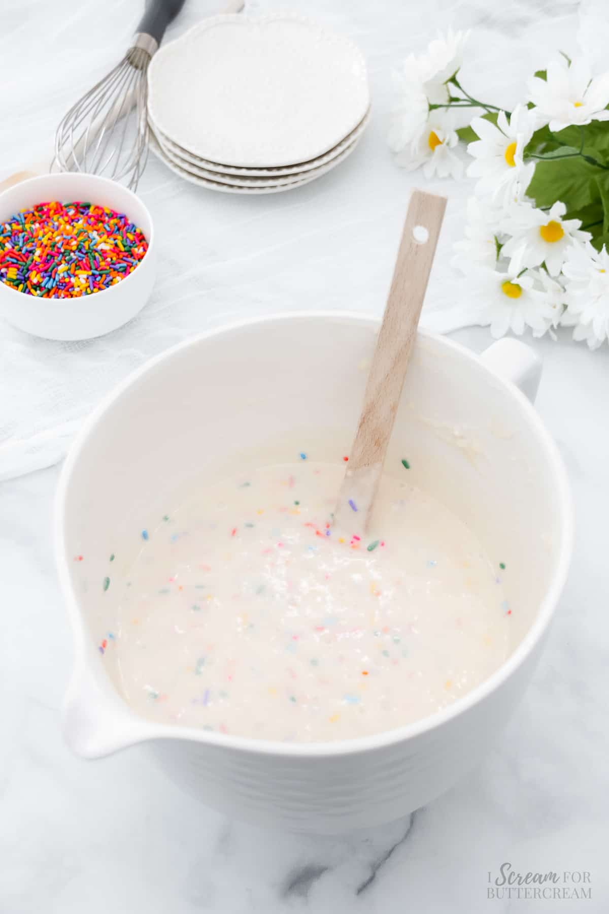 Cake batter with rainbow sprinkles in a white mixing bowl.
