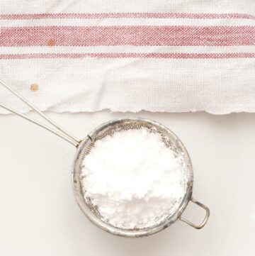 Powdered sugar in a small sifter with a towel.