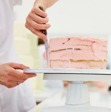 Smoothing buttercream on a pink cake.