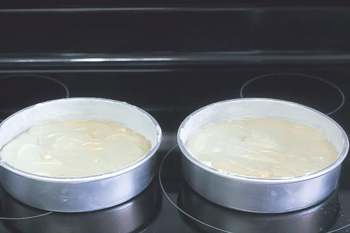 Vanilla cake batter in two cake pans on a stove.