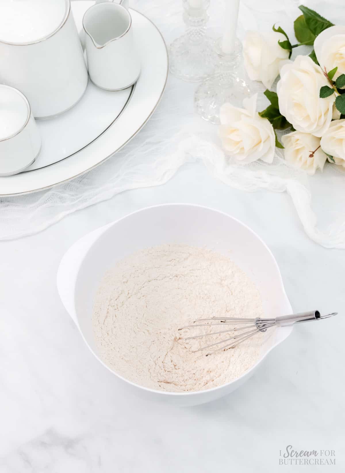 Dry cake batter ingredients in a white bowl with a whisk.
