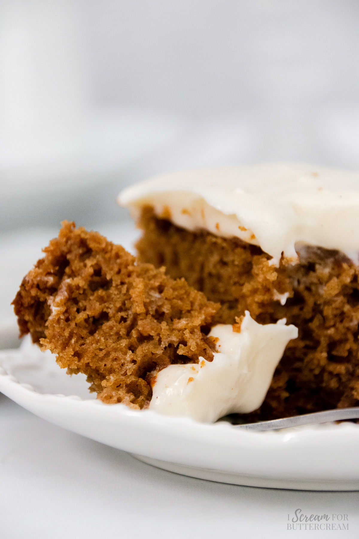 Close up of spice cake with a fork on a white plate.