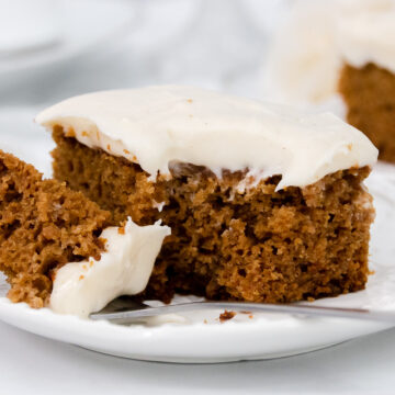 Close up of spice cake with cream cheese icing on a plate with a fork.