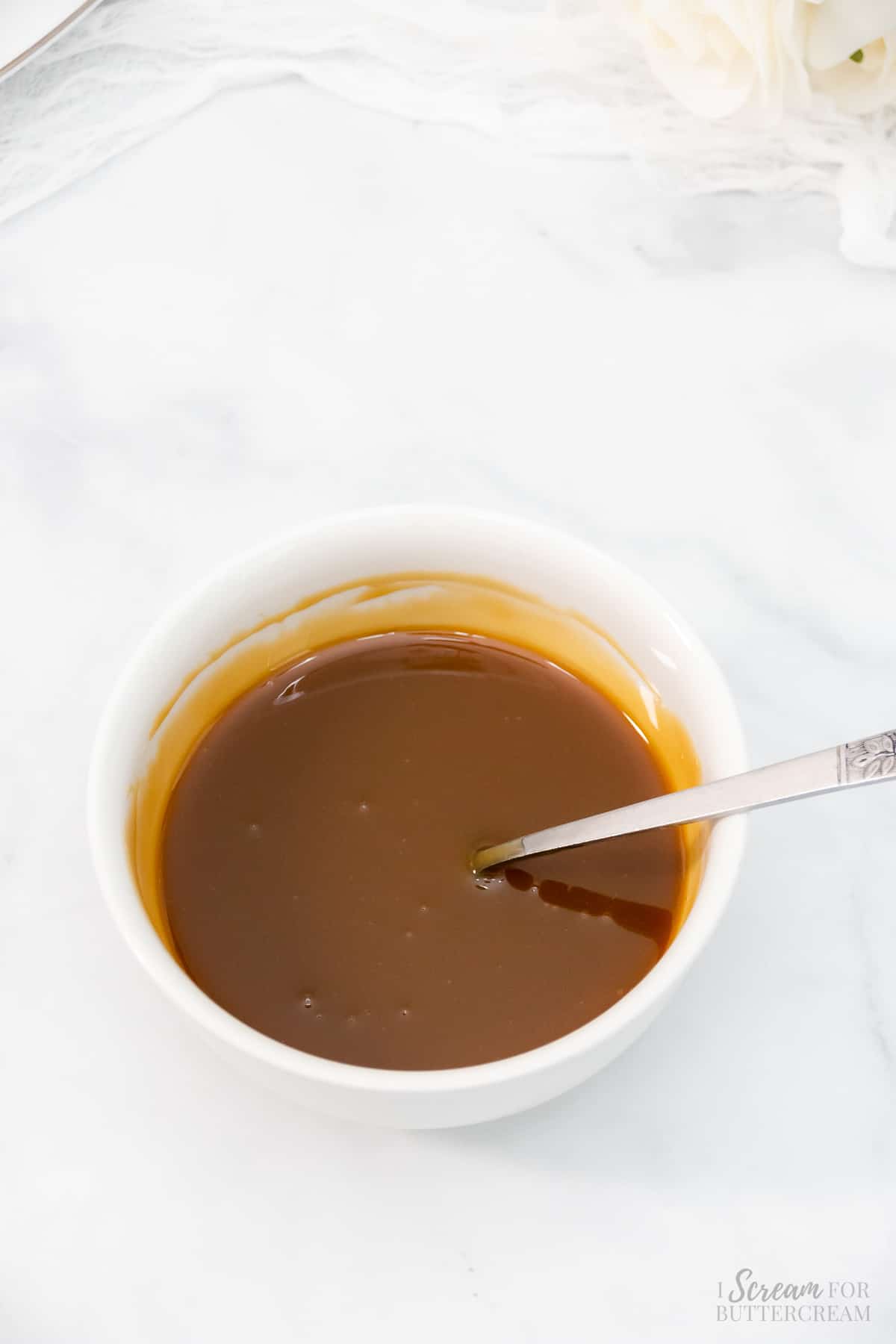 Warmed caramel sauce in a white bowl.