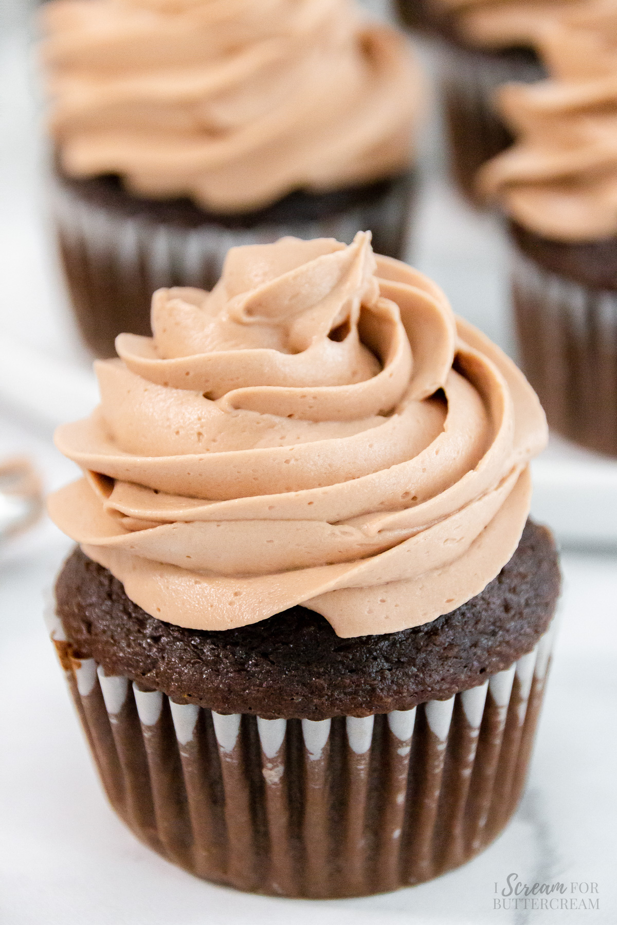 Close up of milk chocolate frosting on a chocolate cupcake.