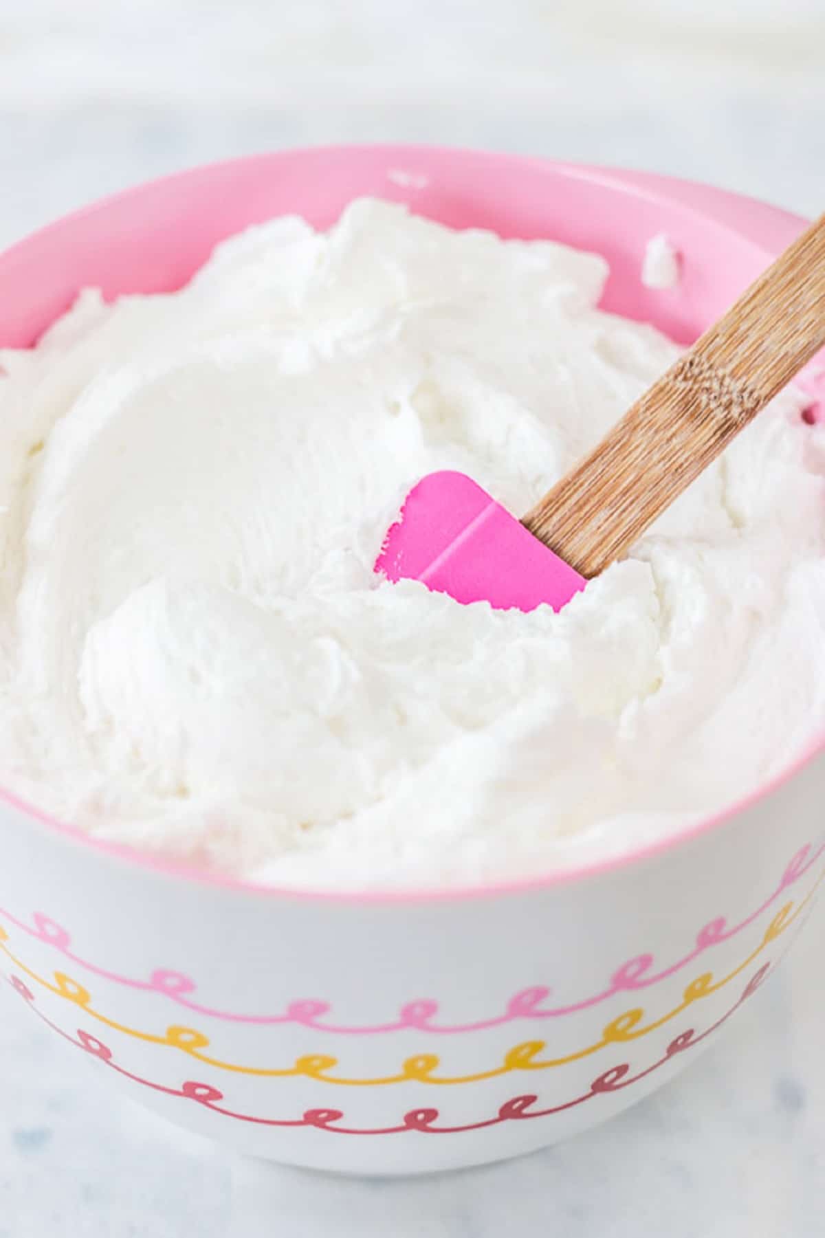 White icing in a pink bowl.