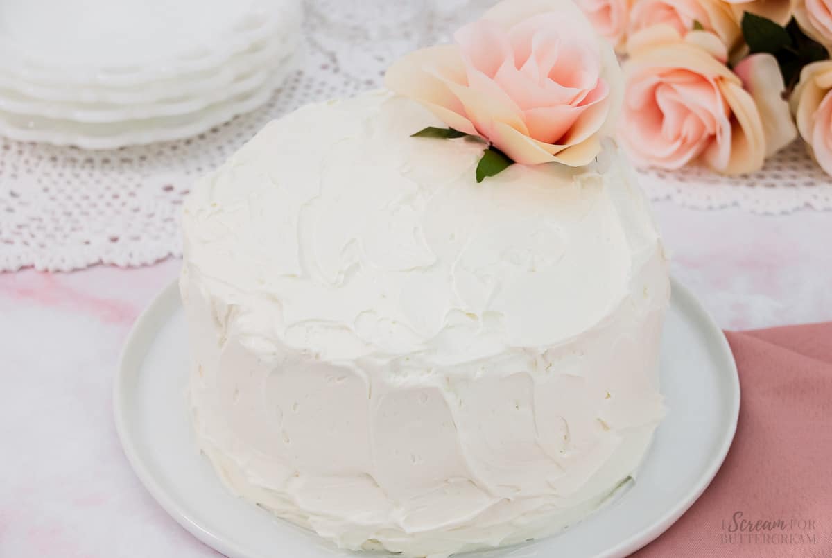 Vanilla cake with white buttercream with a pink flower.