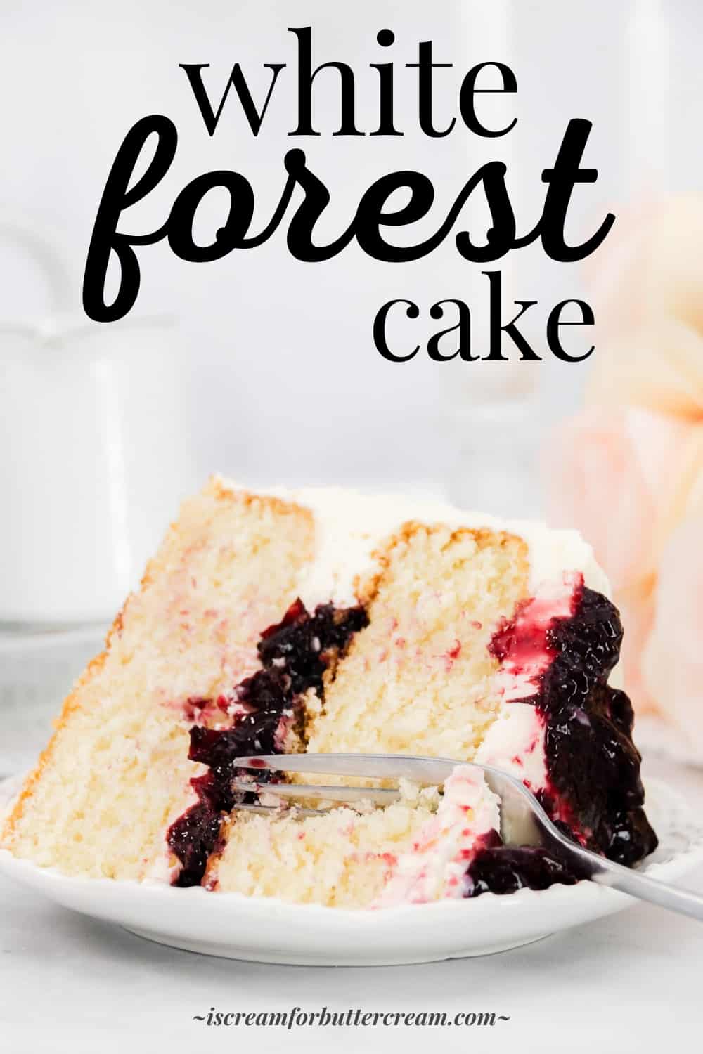 Tall image of slice of white forest cake laying on its side on a white plate with text overlay.