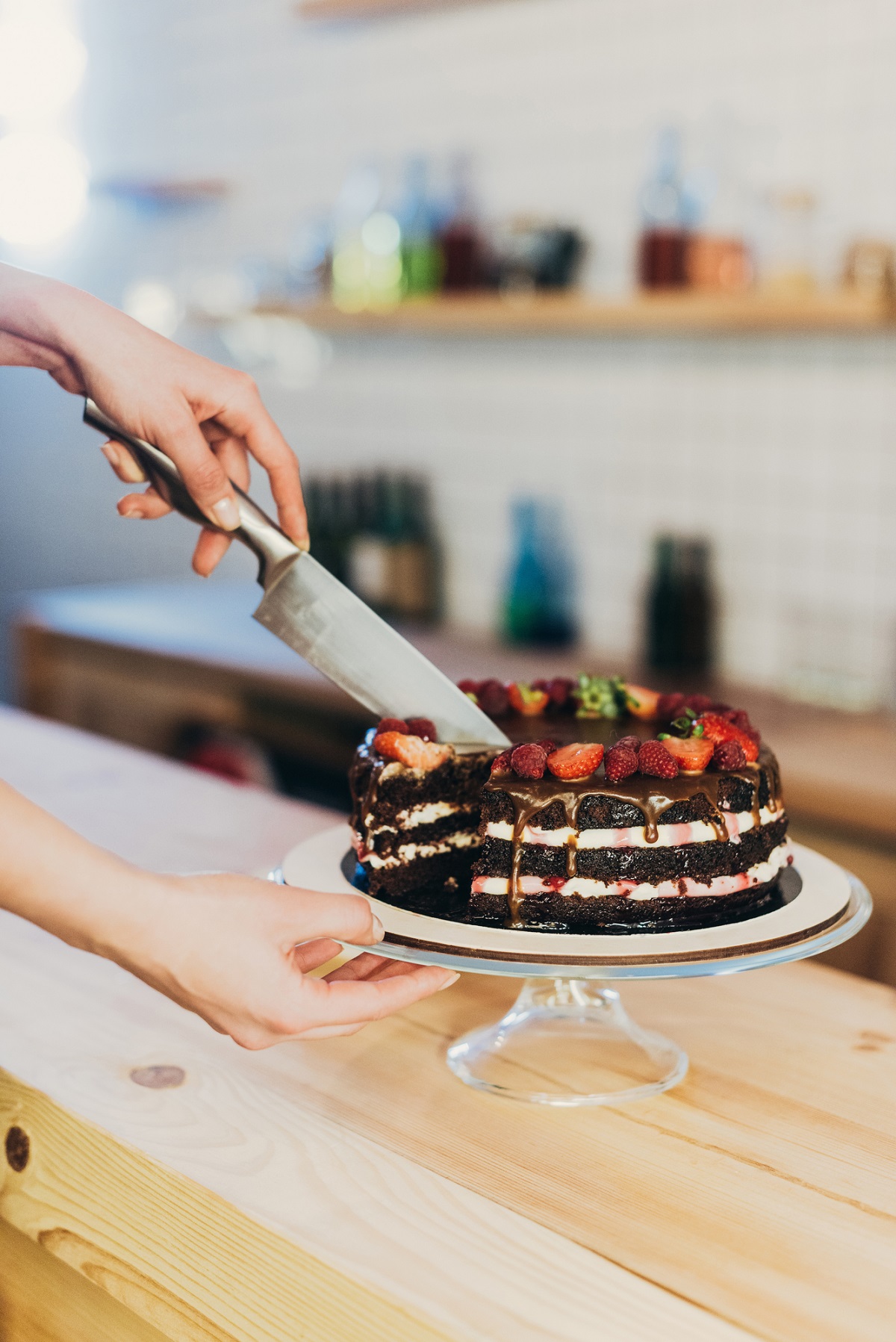 Cutting a chocolate layer cake with fruit.