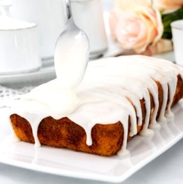 Close up of white cake glaze being spooned over sweet bread.