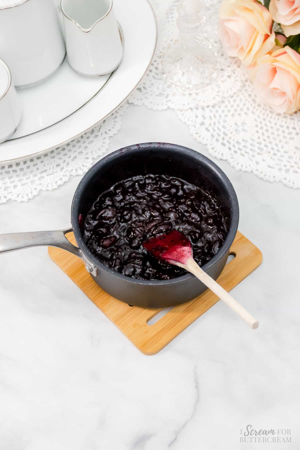 Cooked cherry filling in a saucepan with a wooden spoon.
