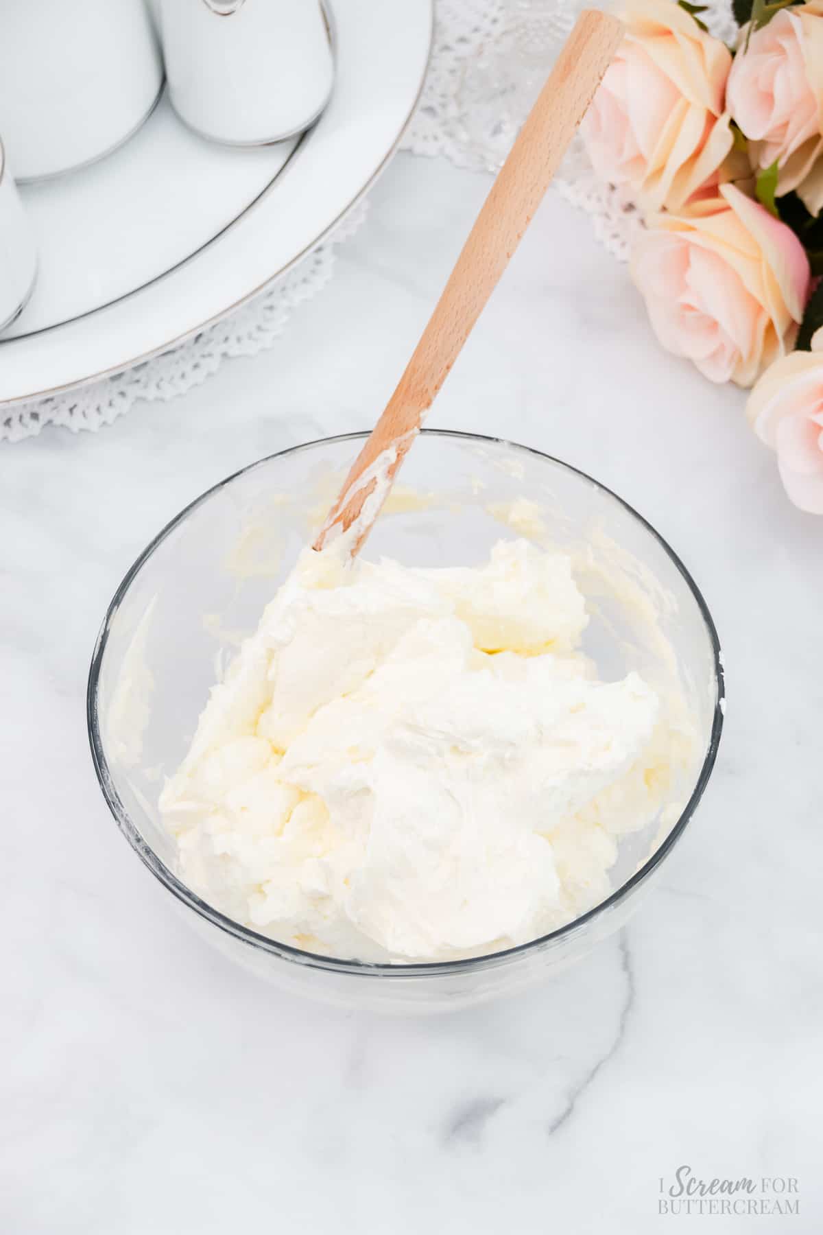 Whipped vanilla buttercream in a clear glass bowl.