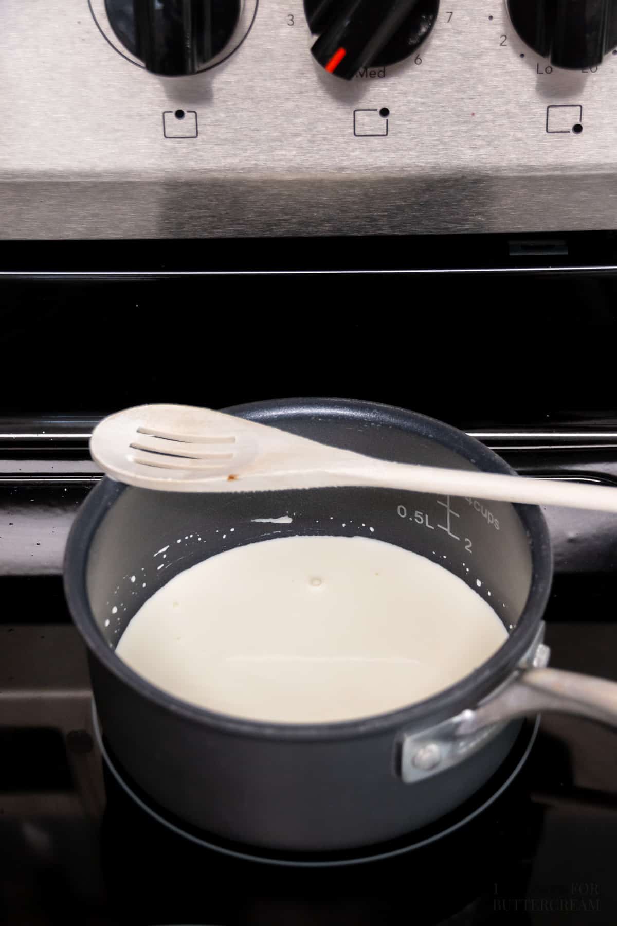 Heated heavy cream in a saucepan on a stove.