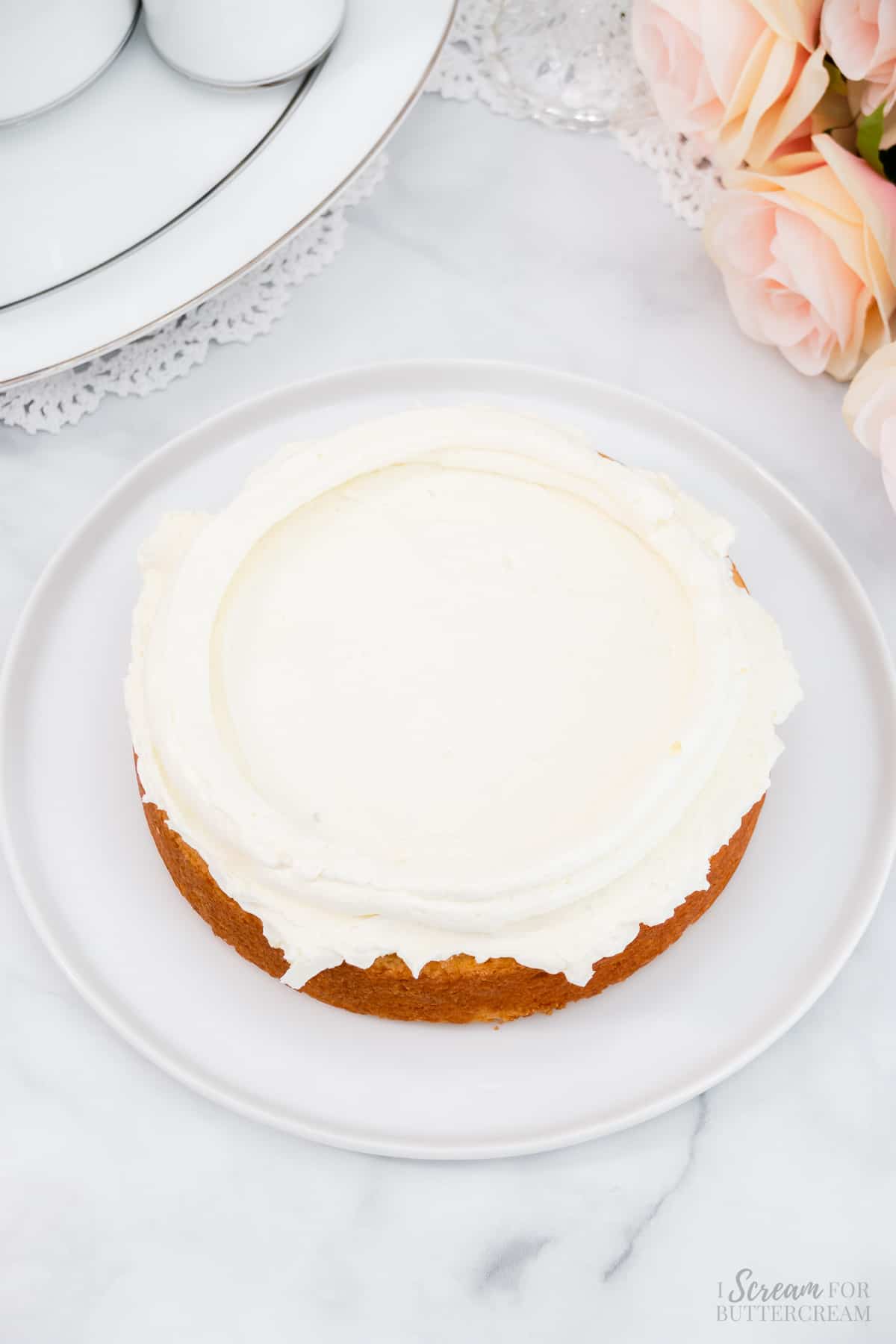 White cake with white whipped frosting on a white platter.