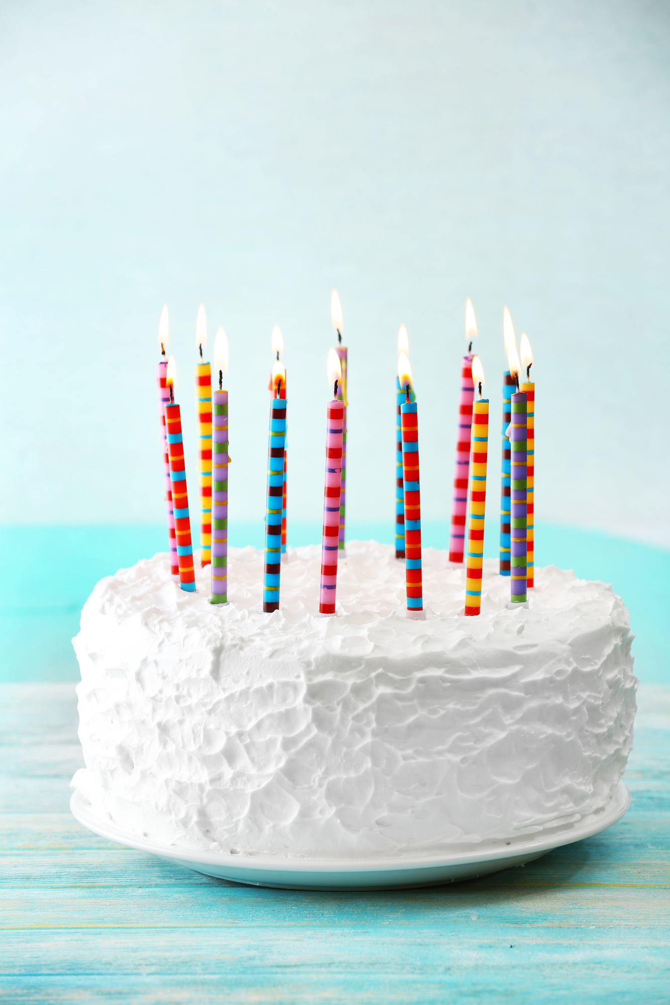 White frosted cakes with candles on a blue background.