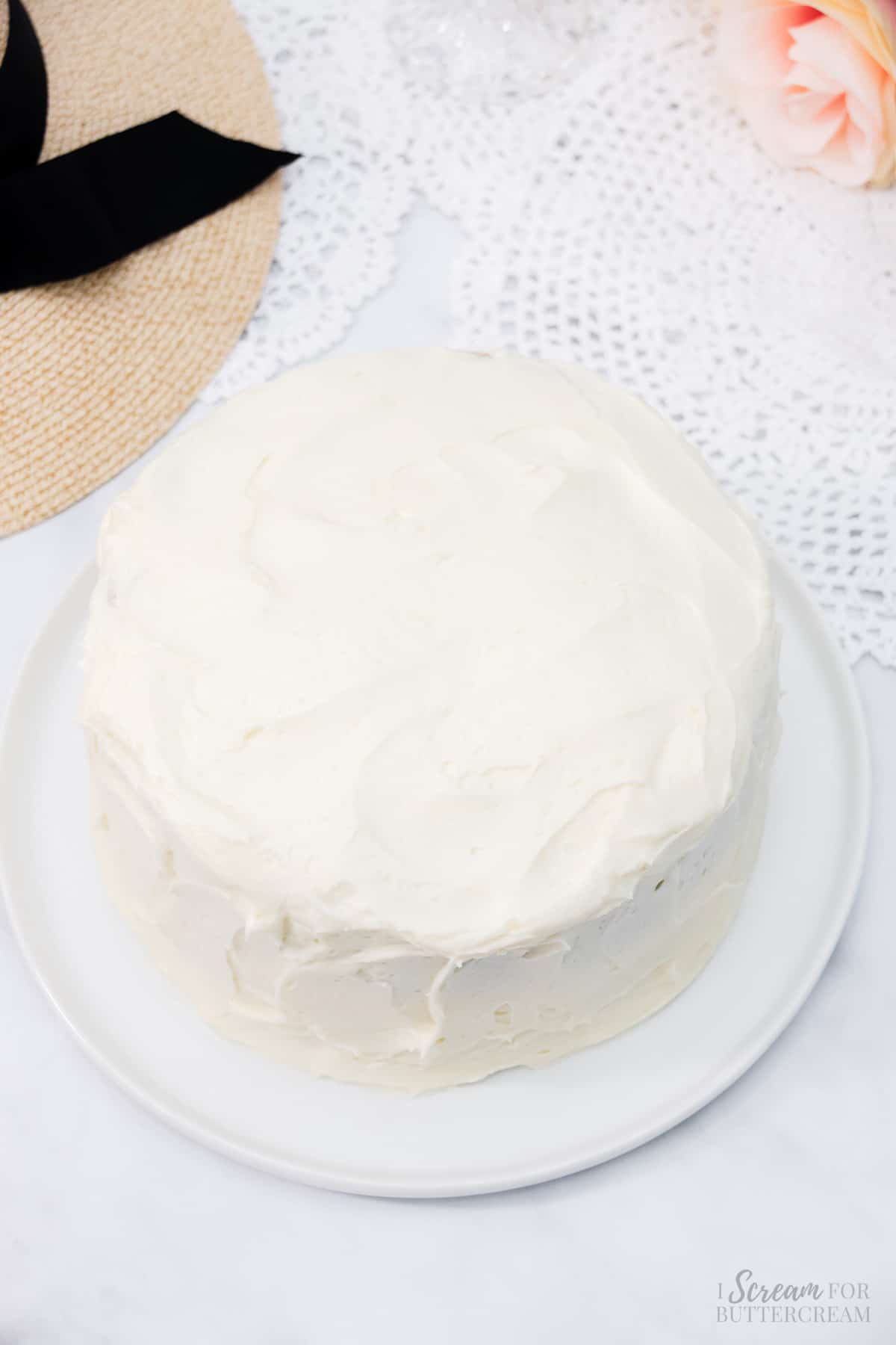 Cream cheese frosting covering a cake on a white platter.
