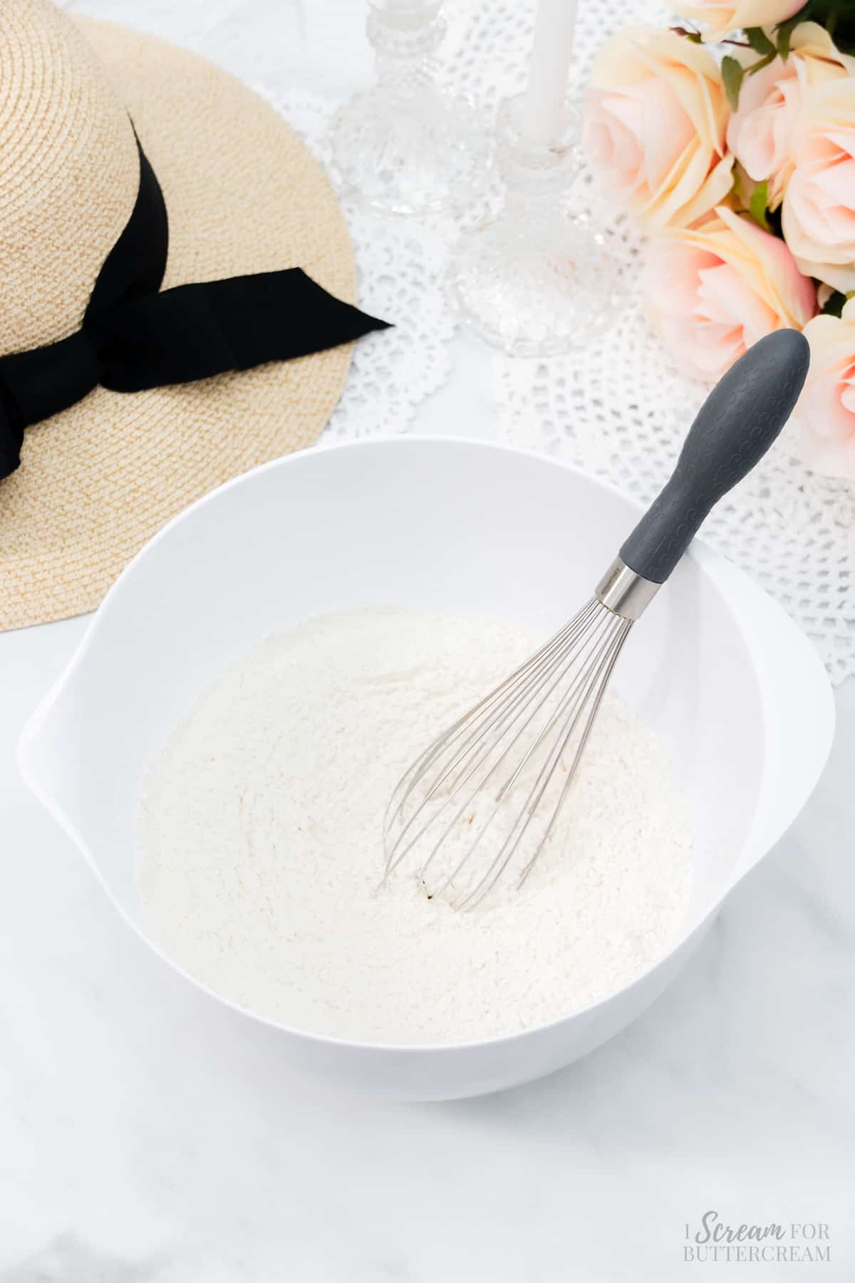 Dry cake ingredients in a white mixing bowl with a whisk.