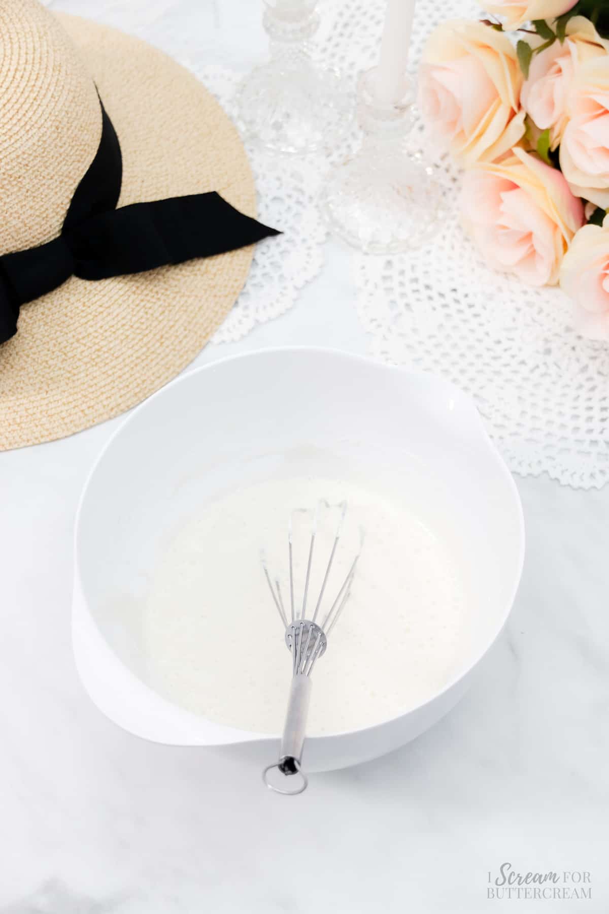 Liquid cake batter ingredients in a white bowl with a whisk.
