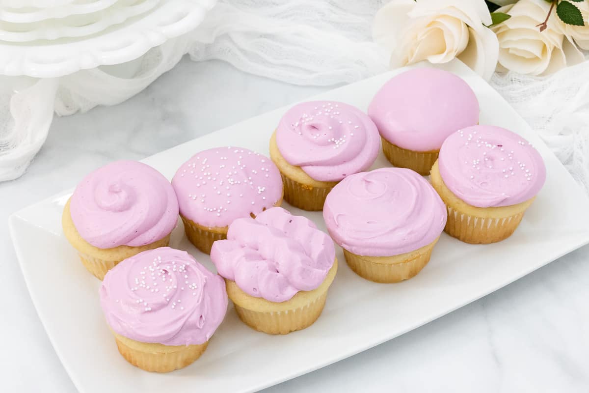 Four vanilla cupcakes with light purple frosting decorated without a piping bag.