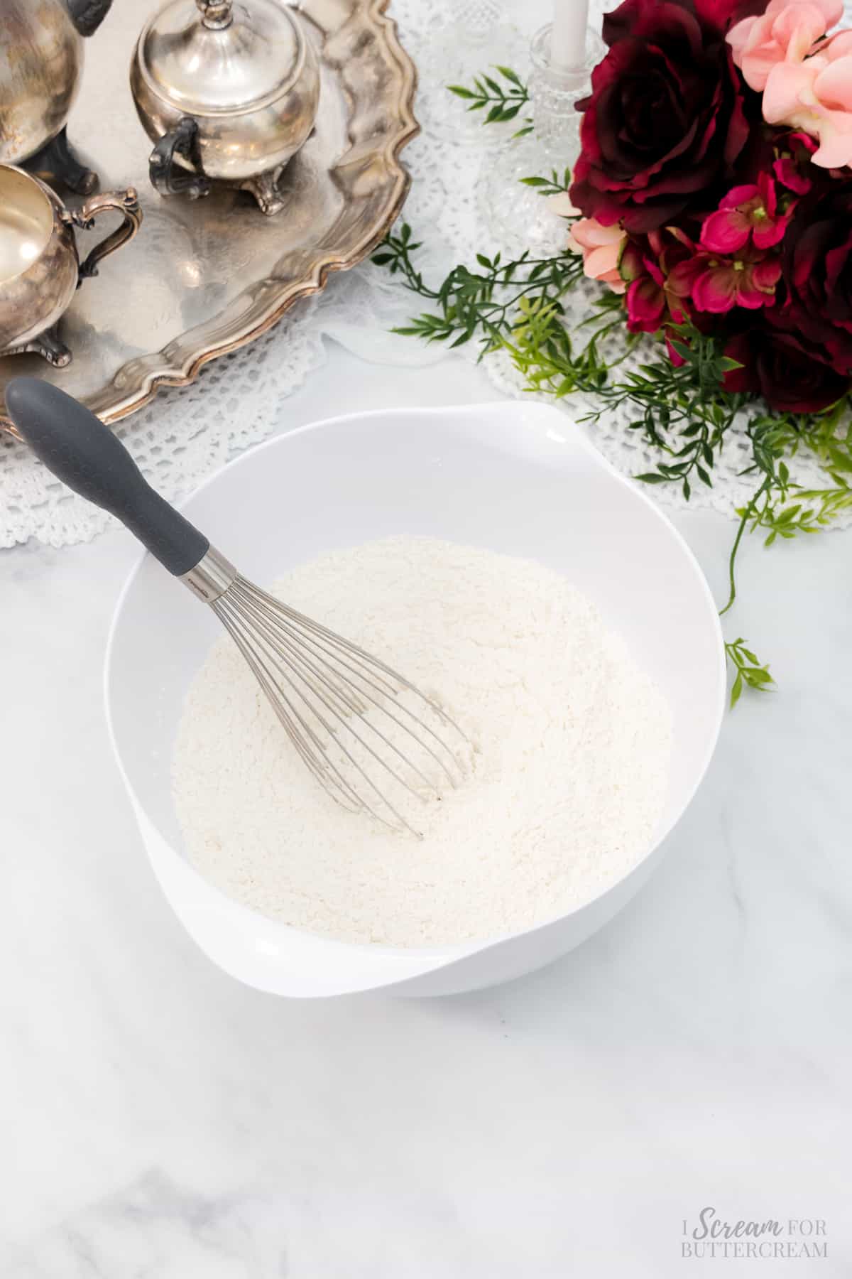 Flour mixture in a white mixing bowl with a whisk.
