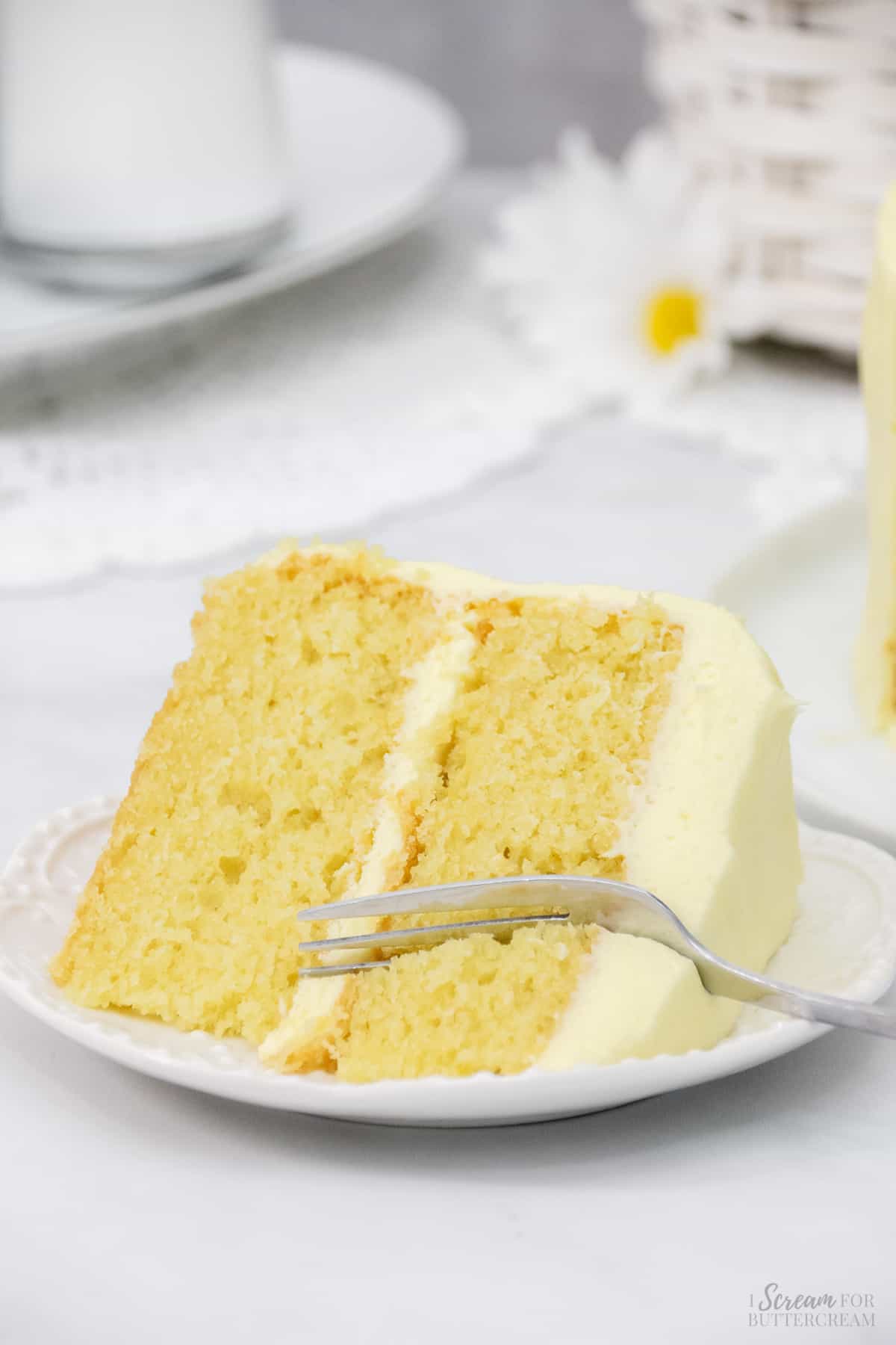 Image of lemon velvet cake with fork on a white plate and white background.