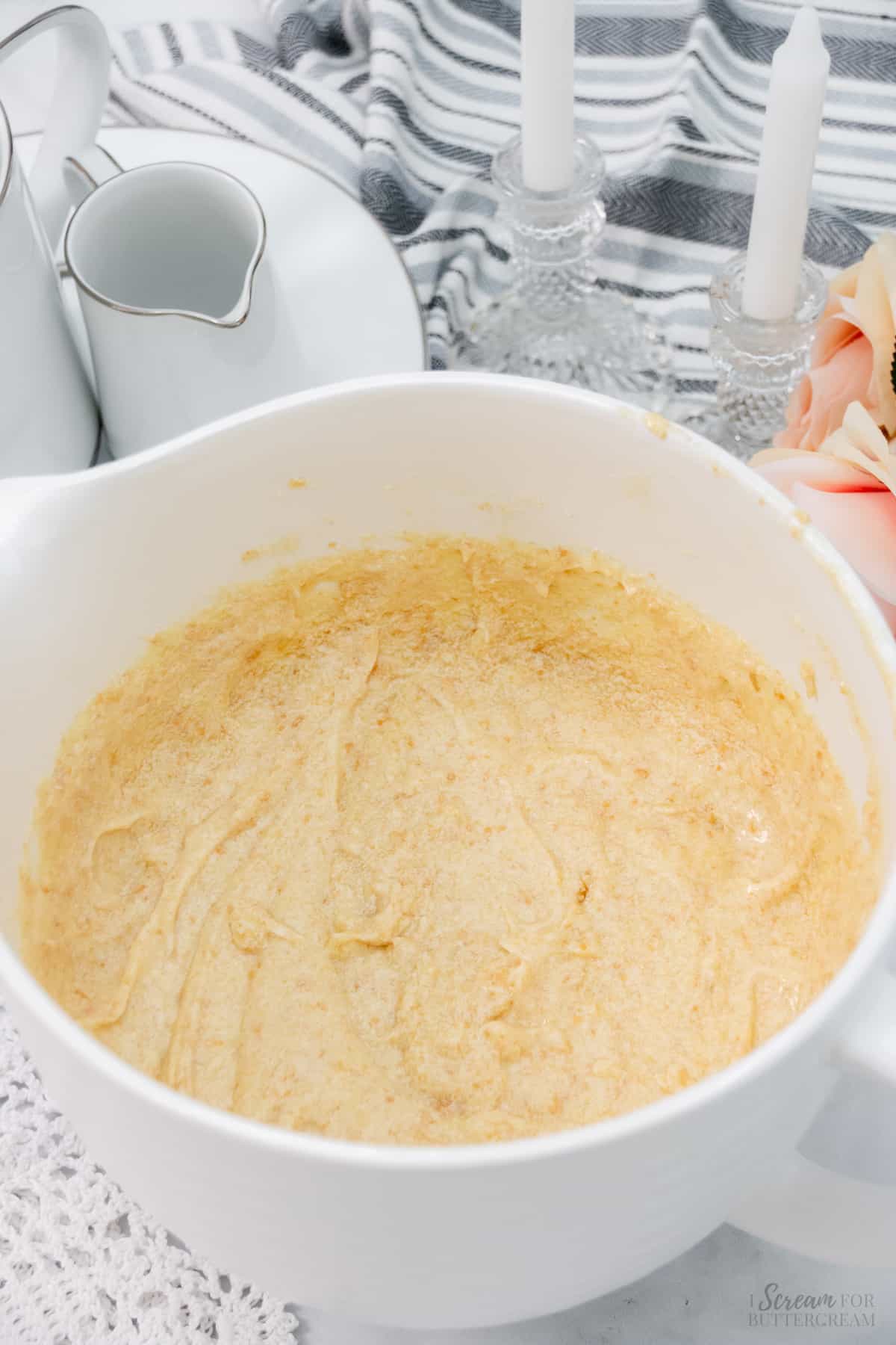 Crushed vanilla wafer crumbs added to vanilla bundt cake batter in a large white mixing bowl.