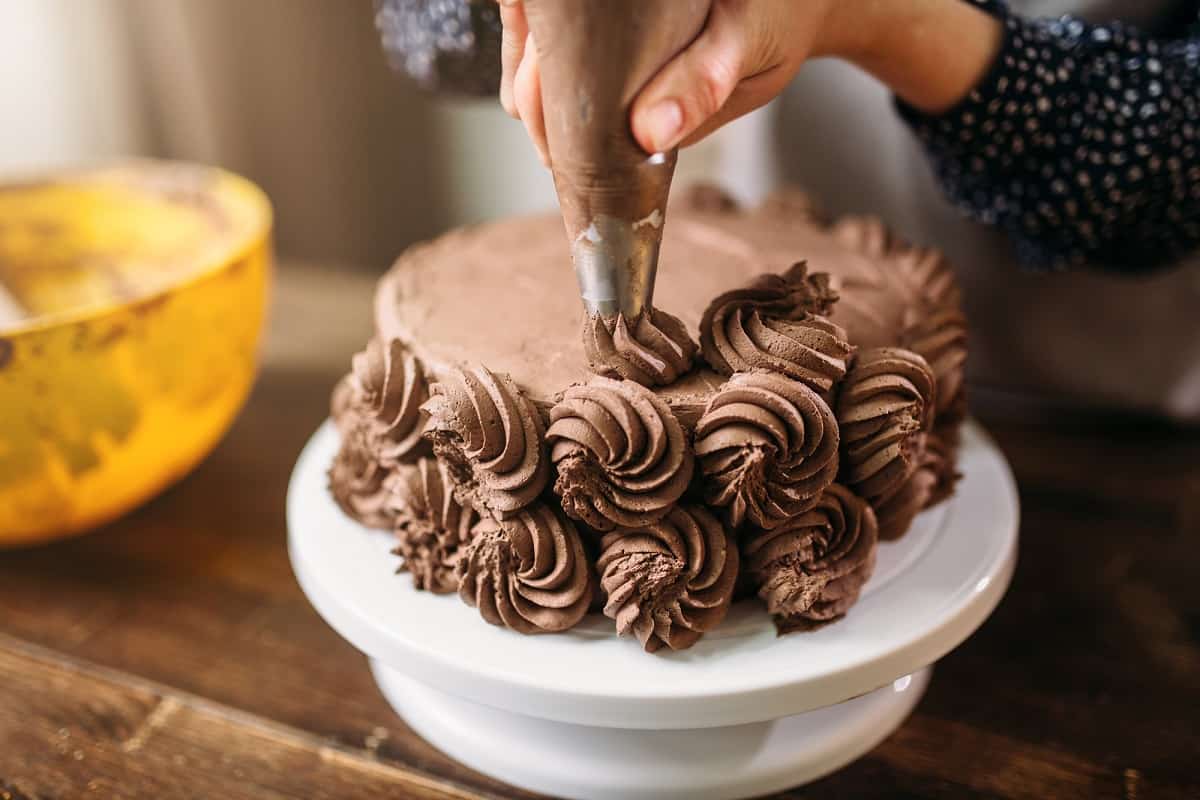 Piping chocolate rosettes onto a cake.