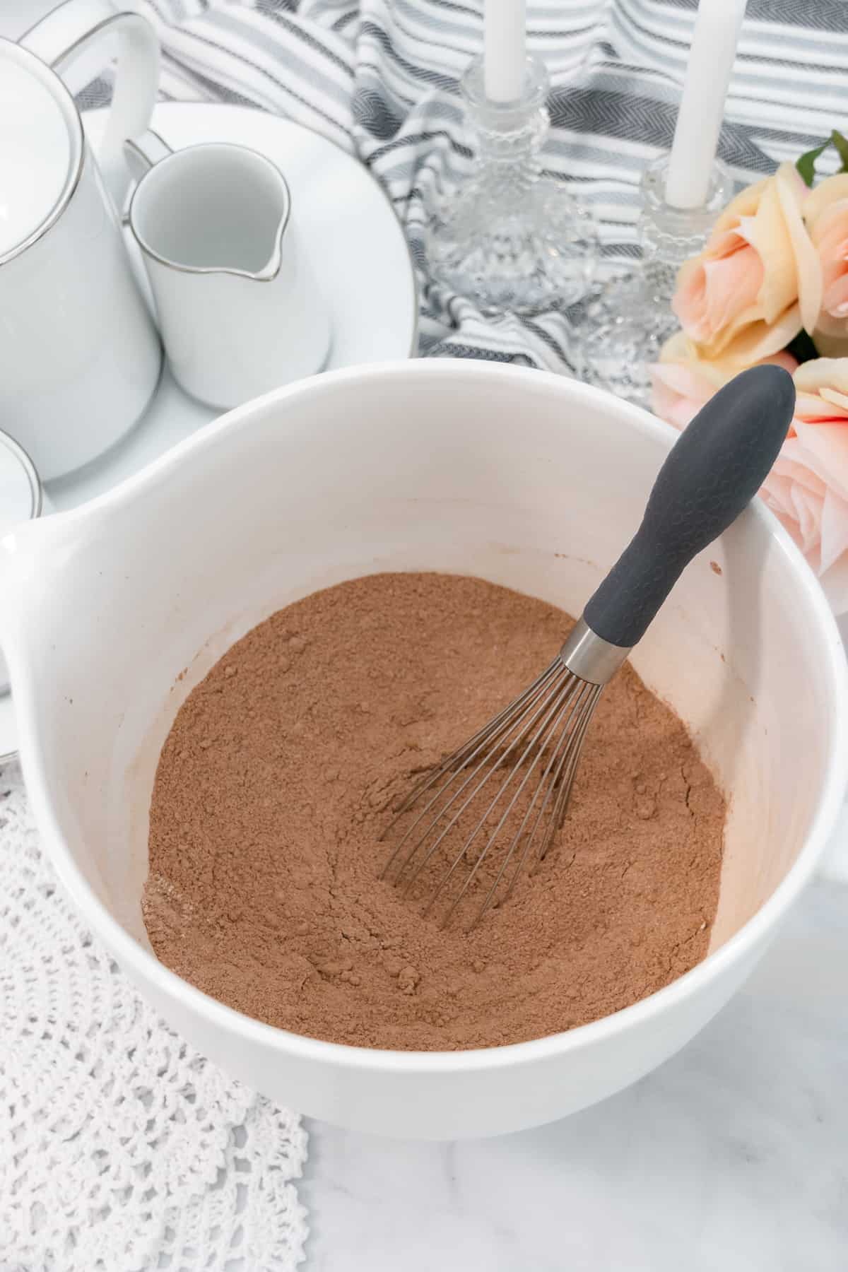 Dry cake batter ingredients in a white bowl with a whisk.