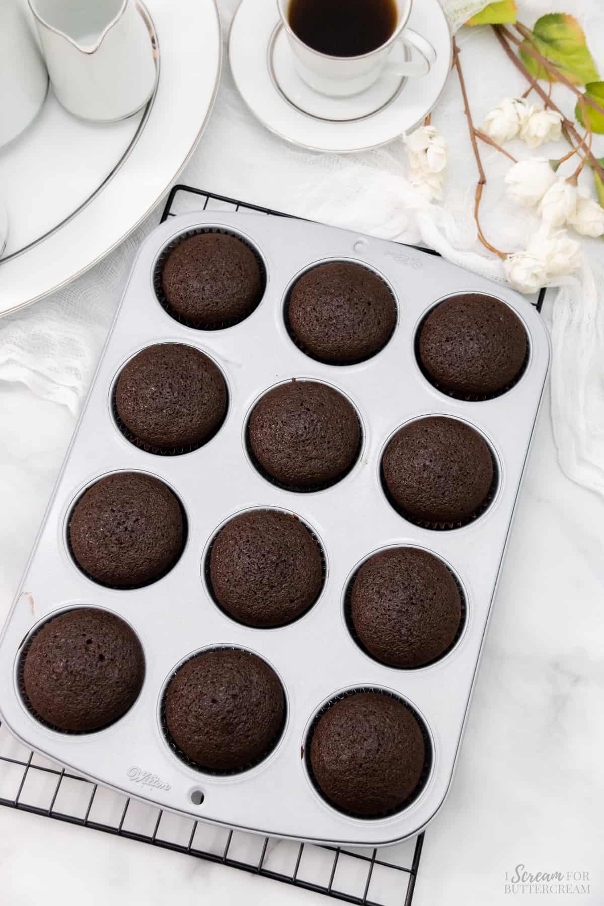 Baked chocolate cupcakes in a cupcake pan on a cooling rack.