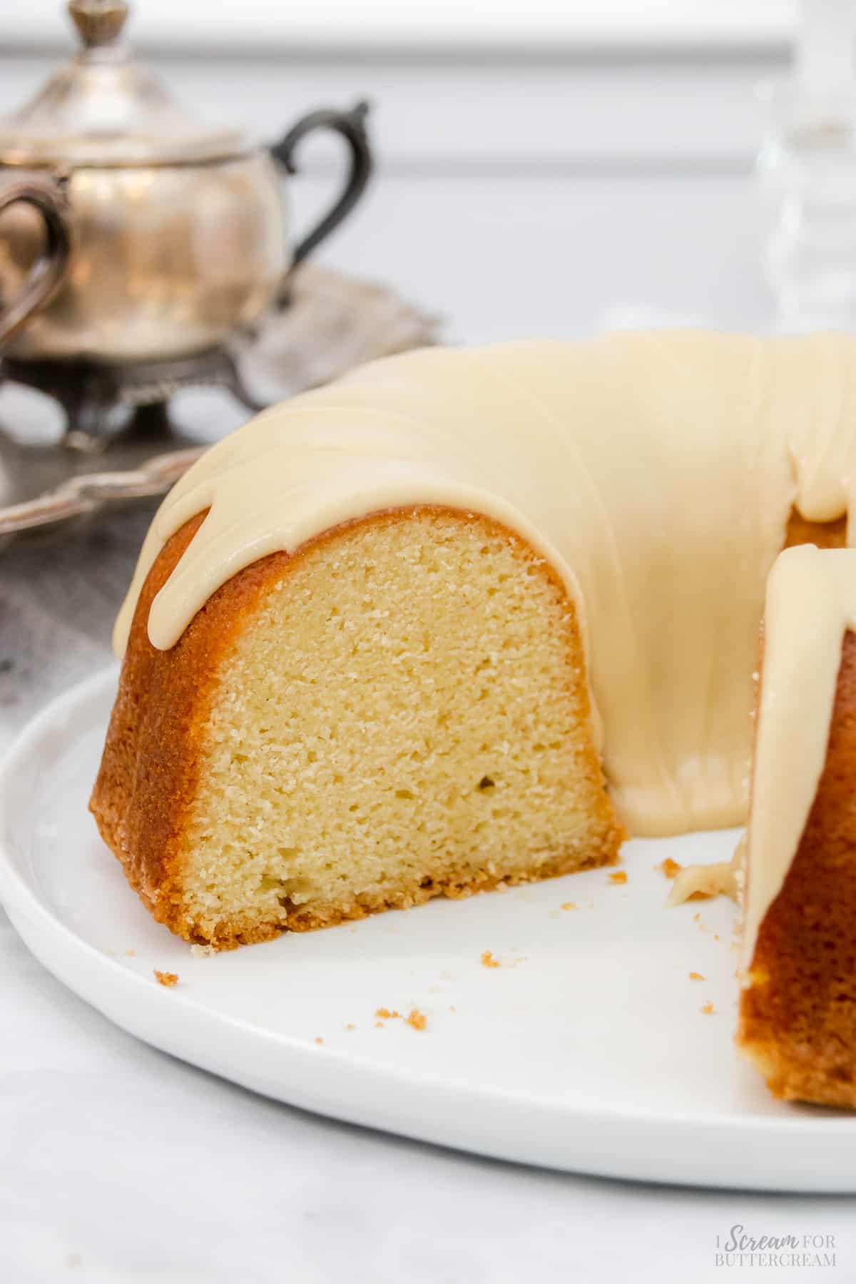 Bundt cake with glaze on a white platter with slices cut out.