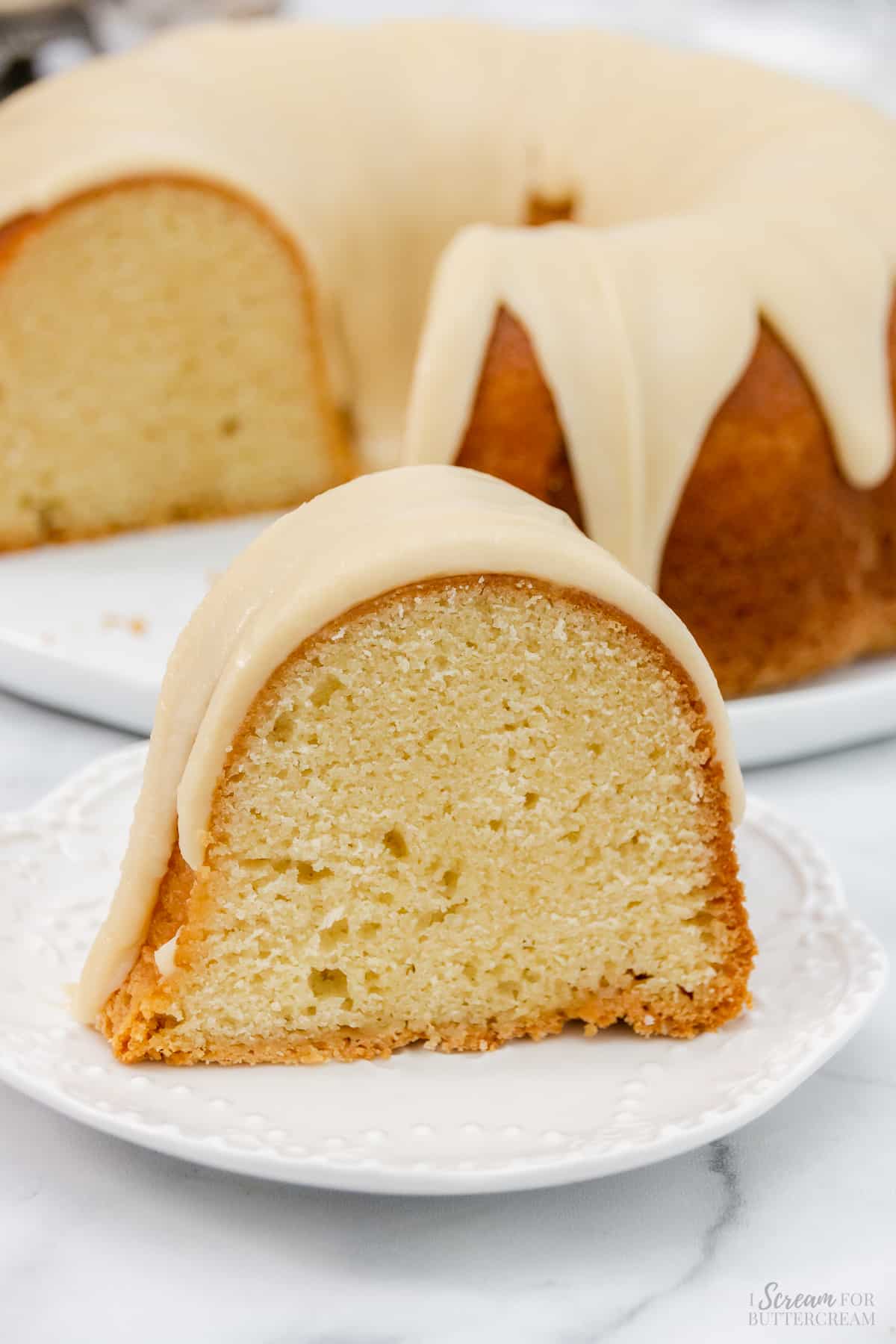 Large slice of vanilla bundt cake made with buttercream on a white plate.