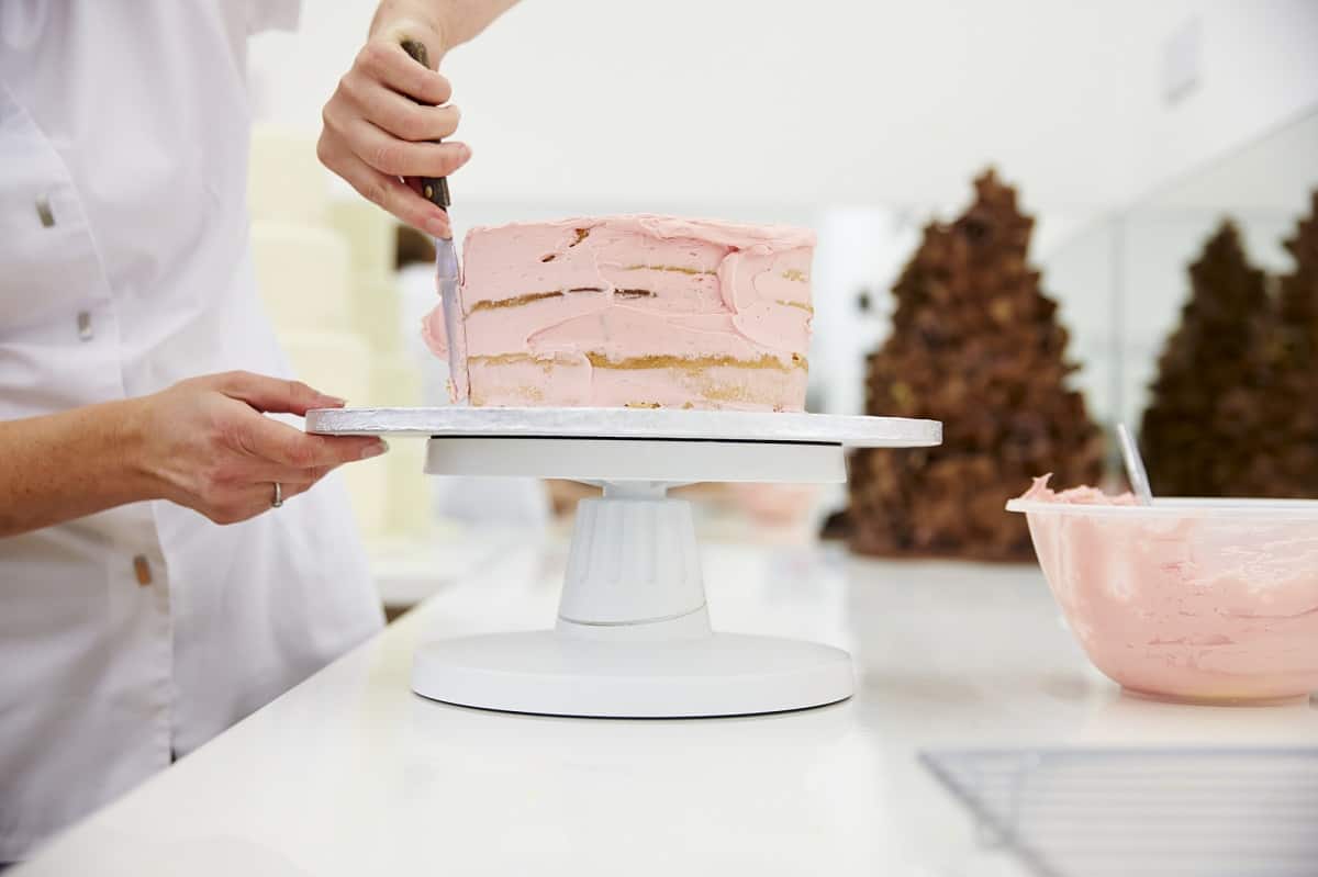 Woman decorating a pink cake.