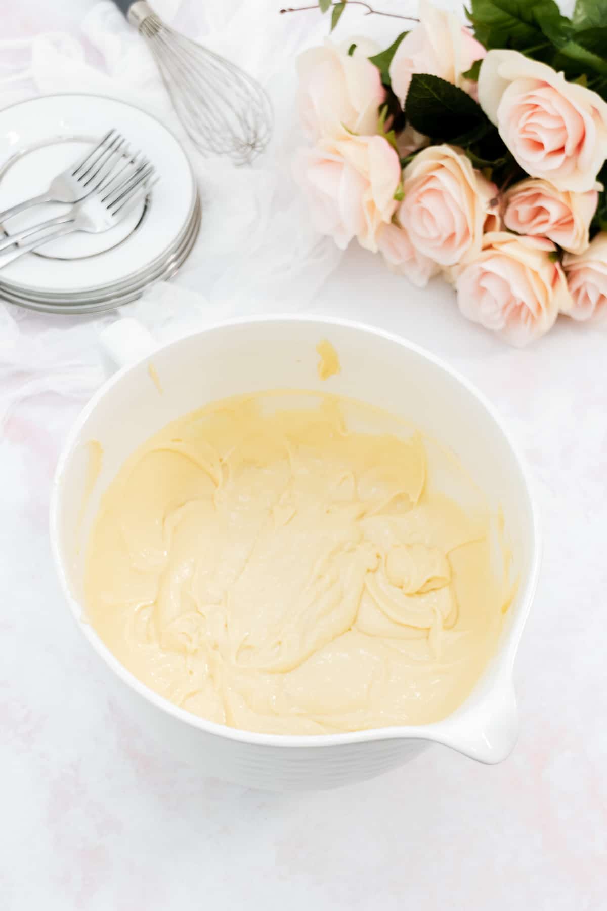 Mixed vanilla cake batter in a large white mixing bowl.