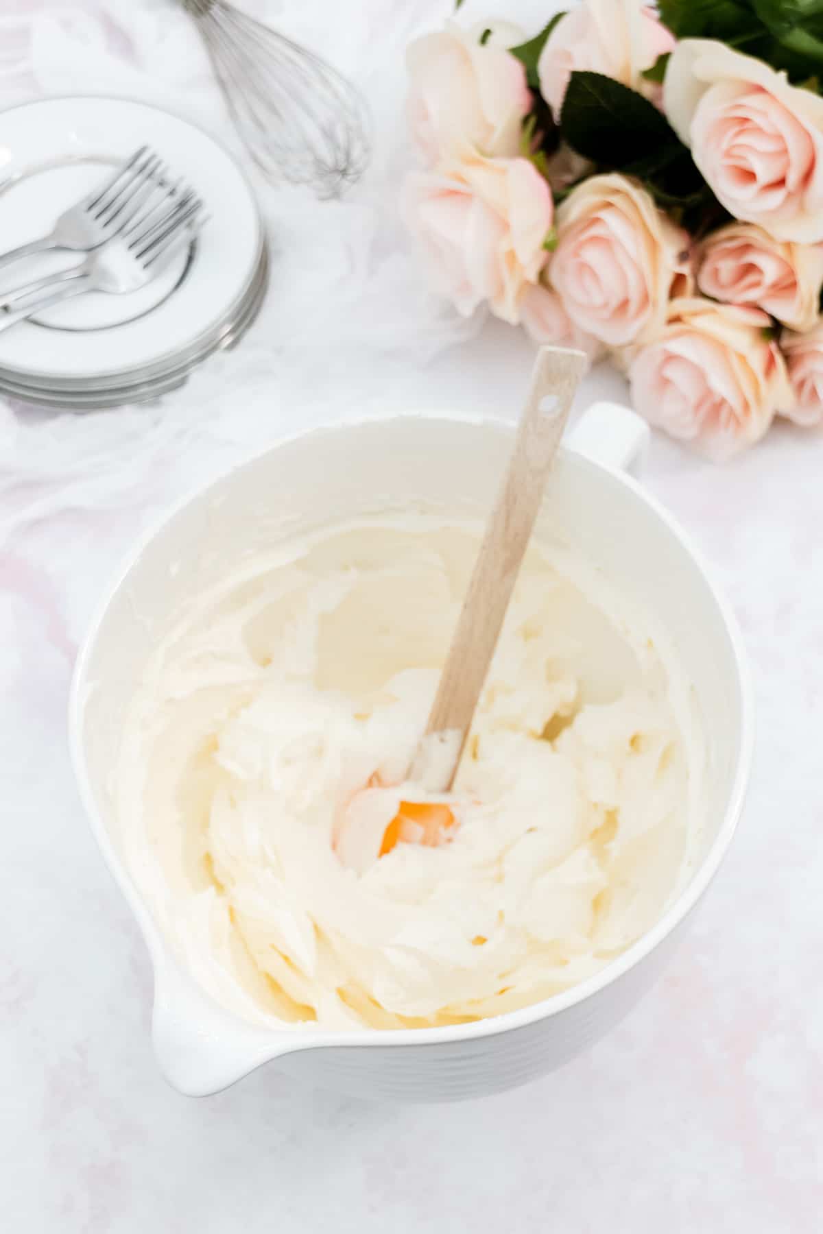 Vanilla frosting made in a large white mixing bowl.
