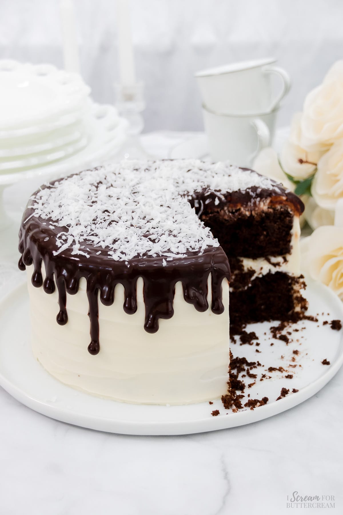 Decorated chocolate cake covered in cream cheese frosting with coconut and chocolate on top.