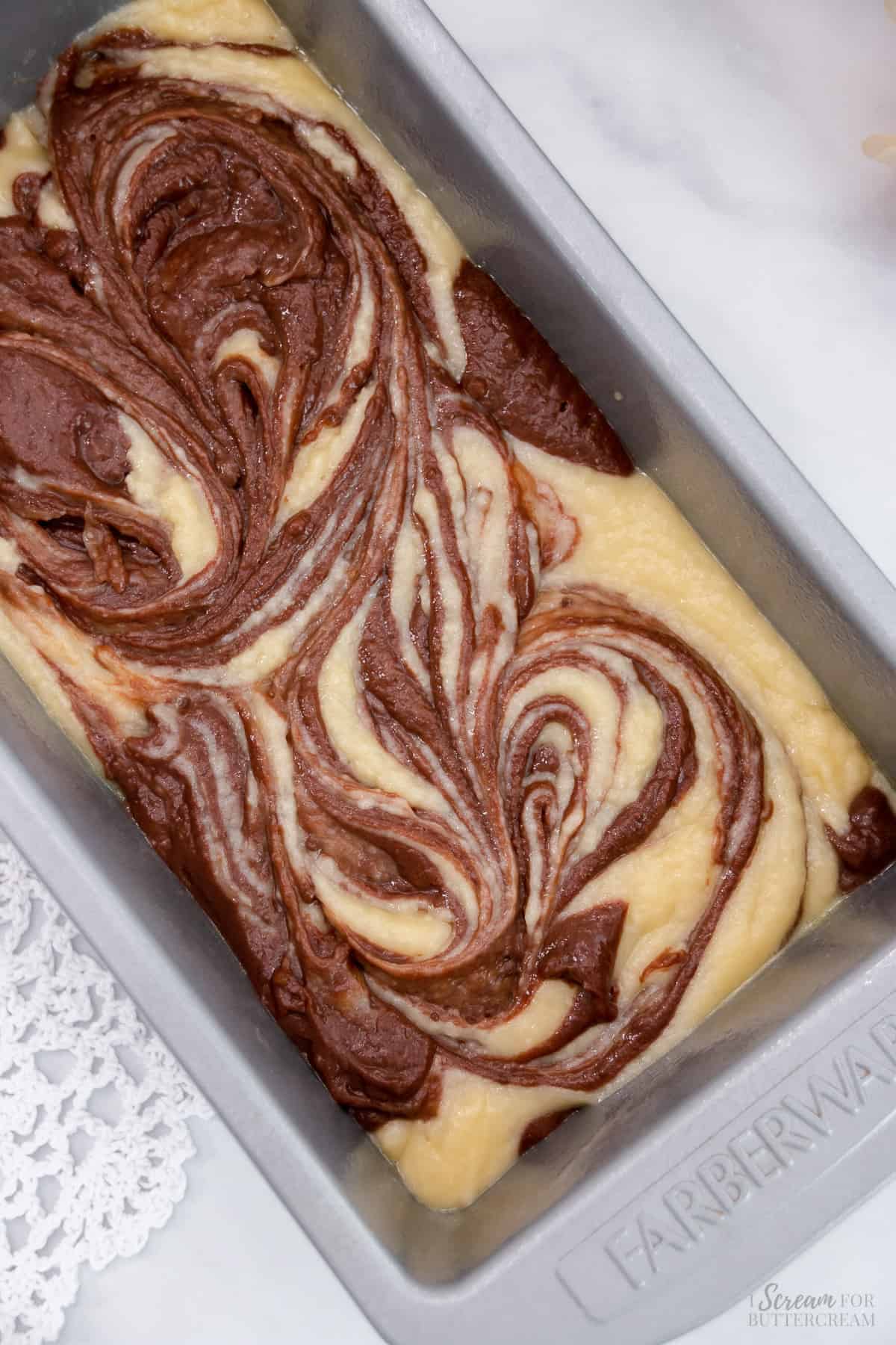 Swirled chocolate and vanilla cake batter in a loaf pan.