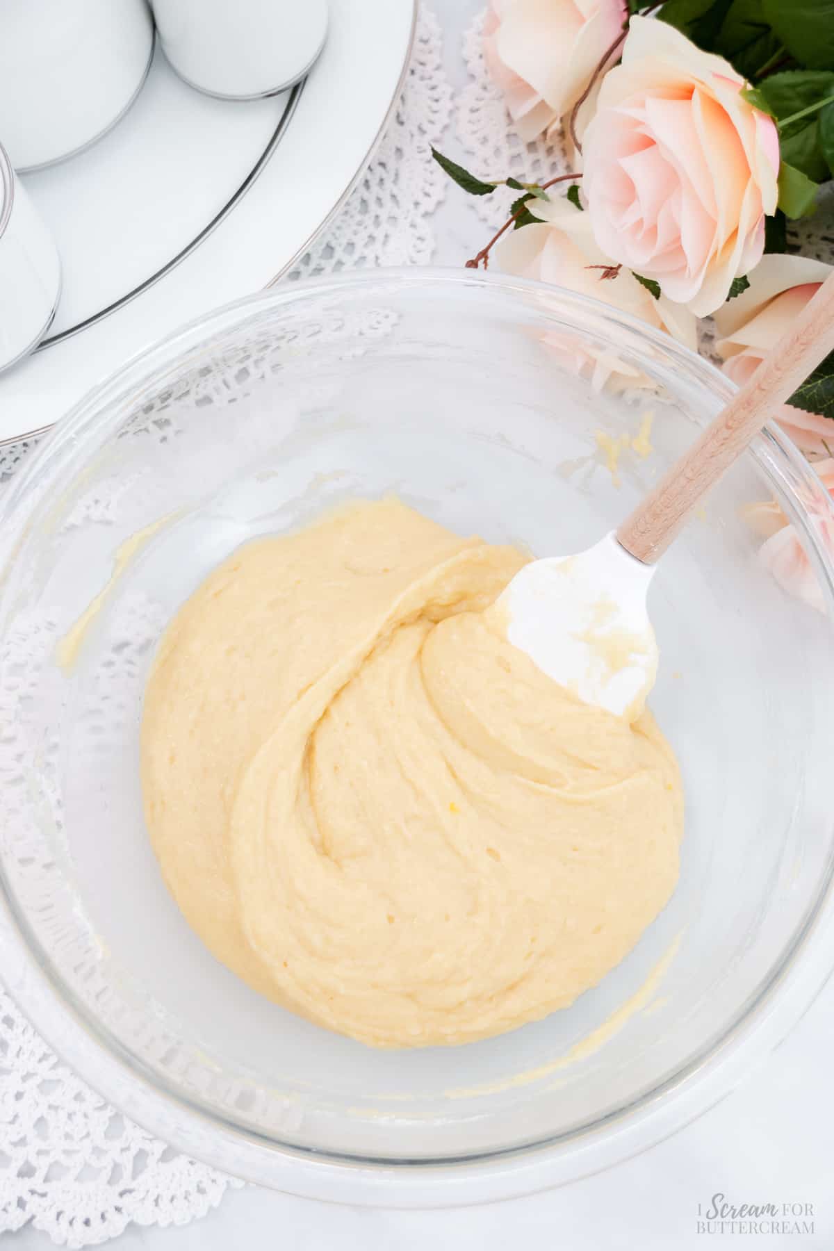 Mixed vanilla cake batter in a mixing bowl with a spatula.