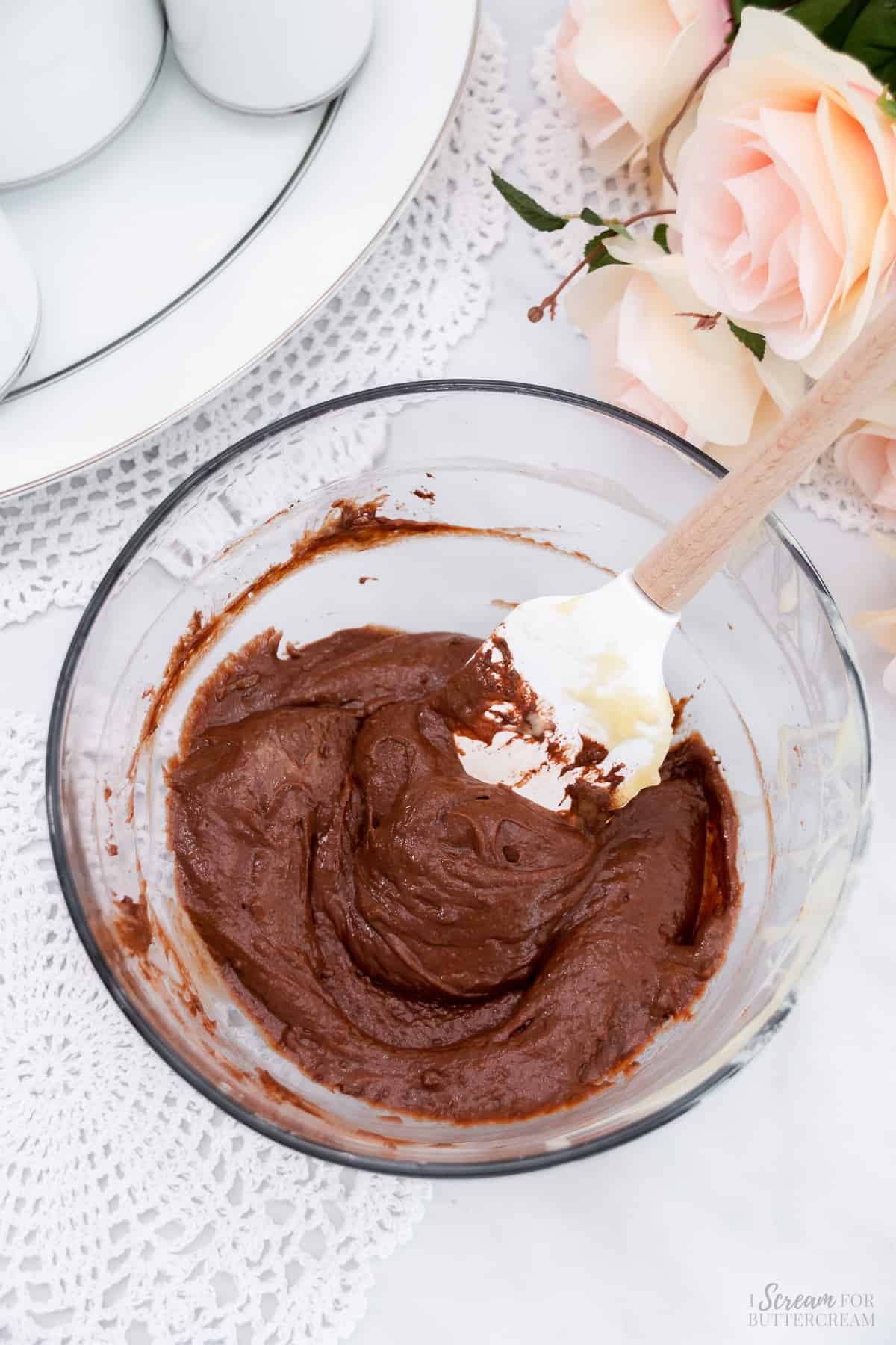 Chocolate cake batter in a glass mixing bowl with a spatula.