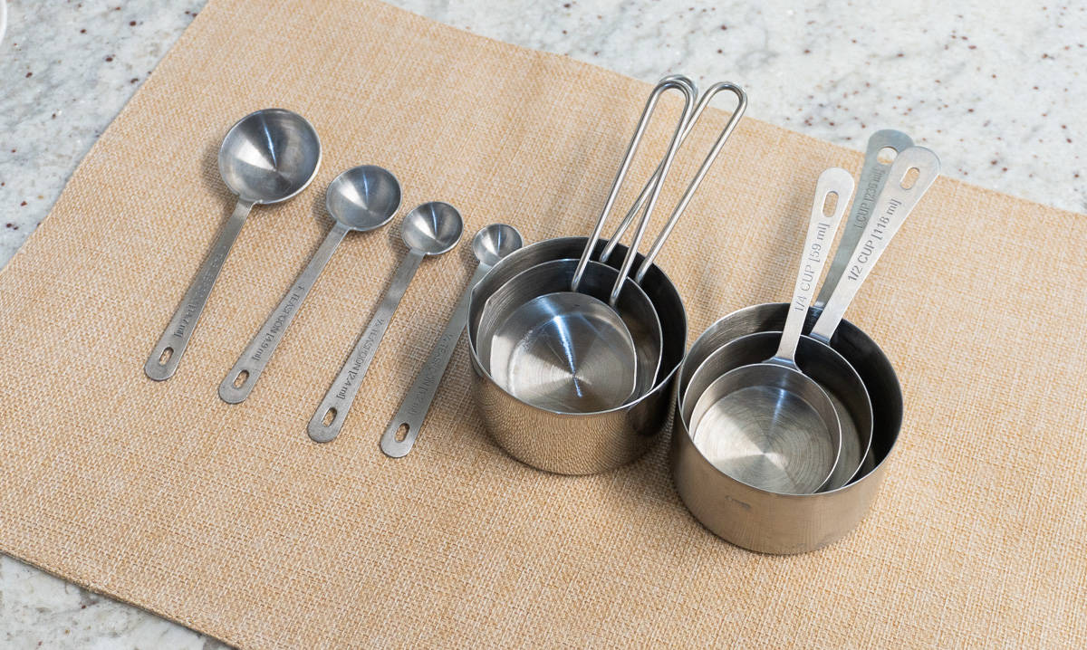 Silver measuring cups and spoons on a counter top.