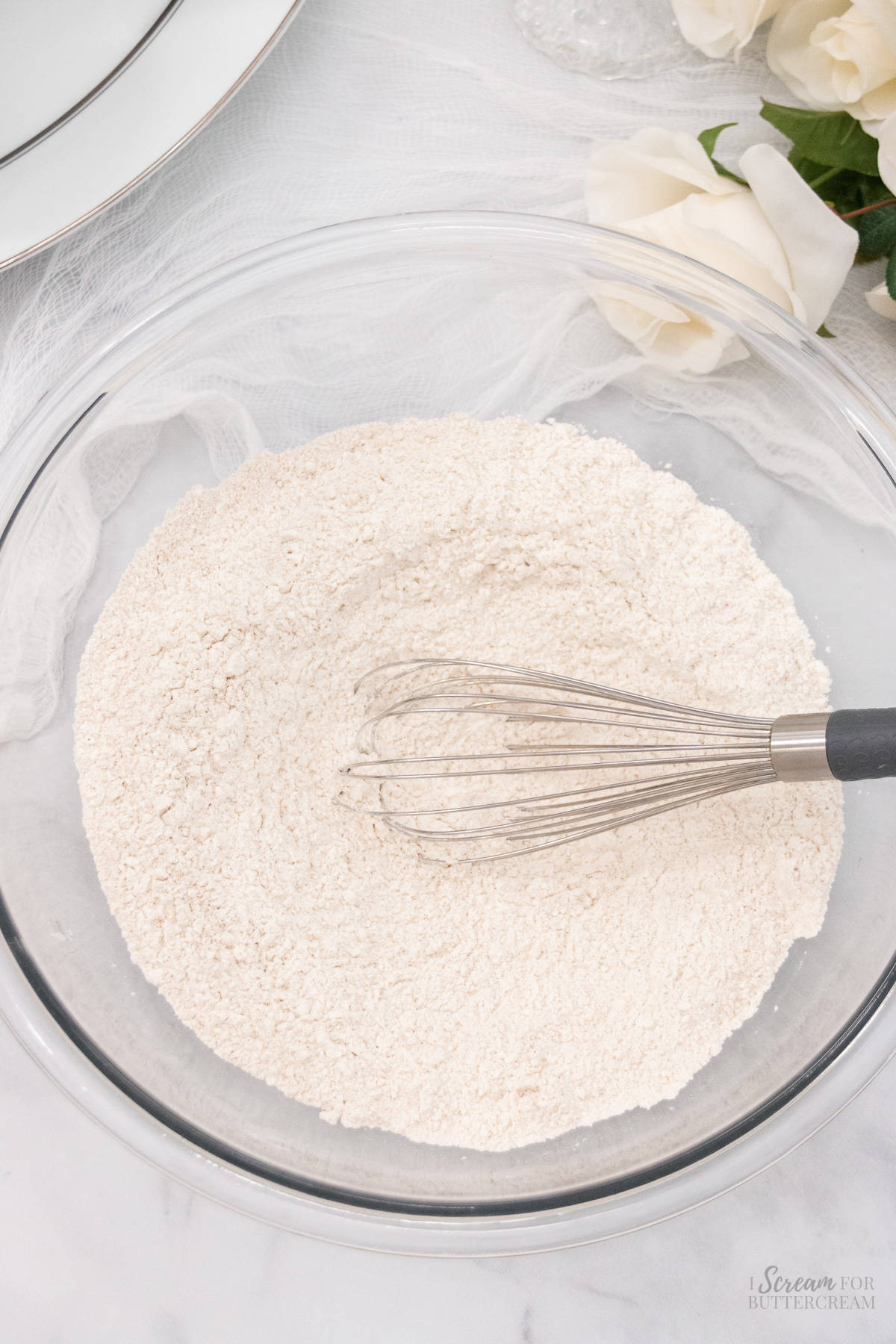 Dry cake ingredients in a glass bowl with a whisk.