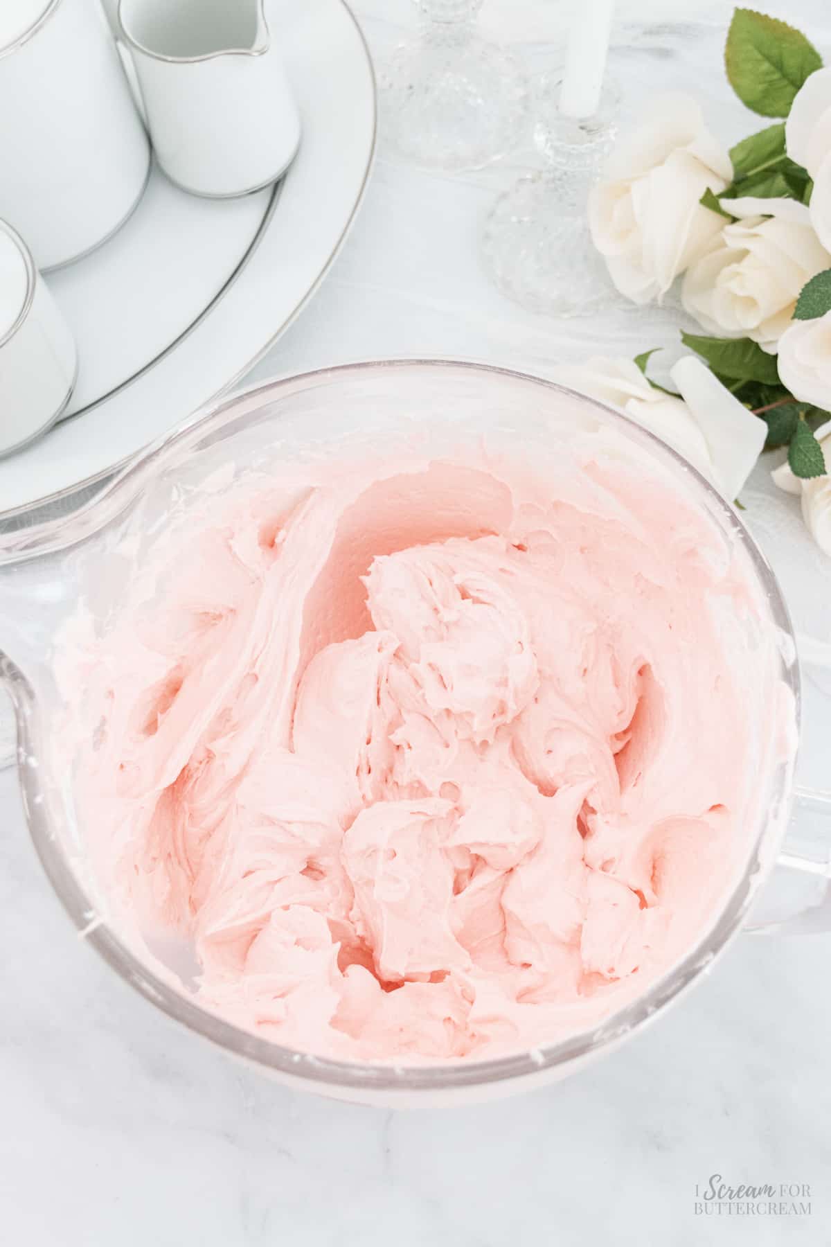 Mixed strawberry buttercream in a glass bowl.