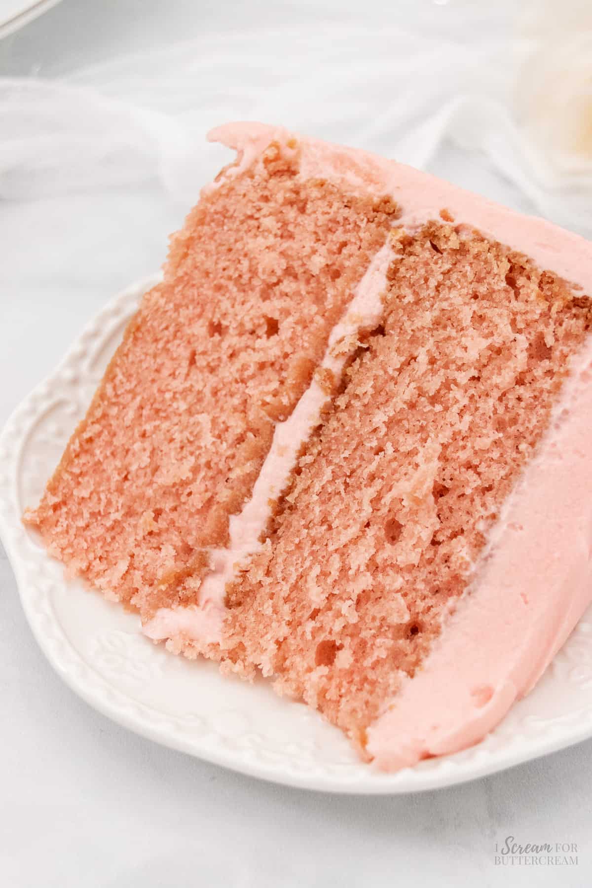Top down image of a large slice of strawberry cake from scratch on a white plate.