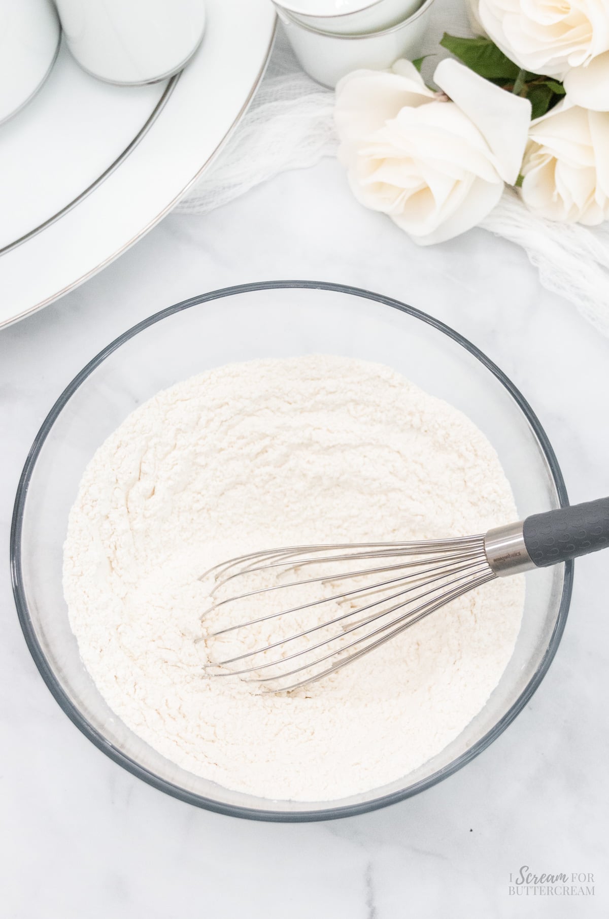Dry cake batter ingredients in a glass bowl with a whisk.