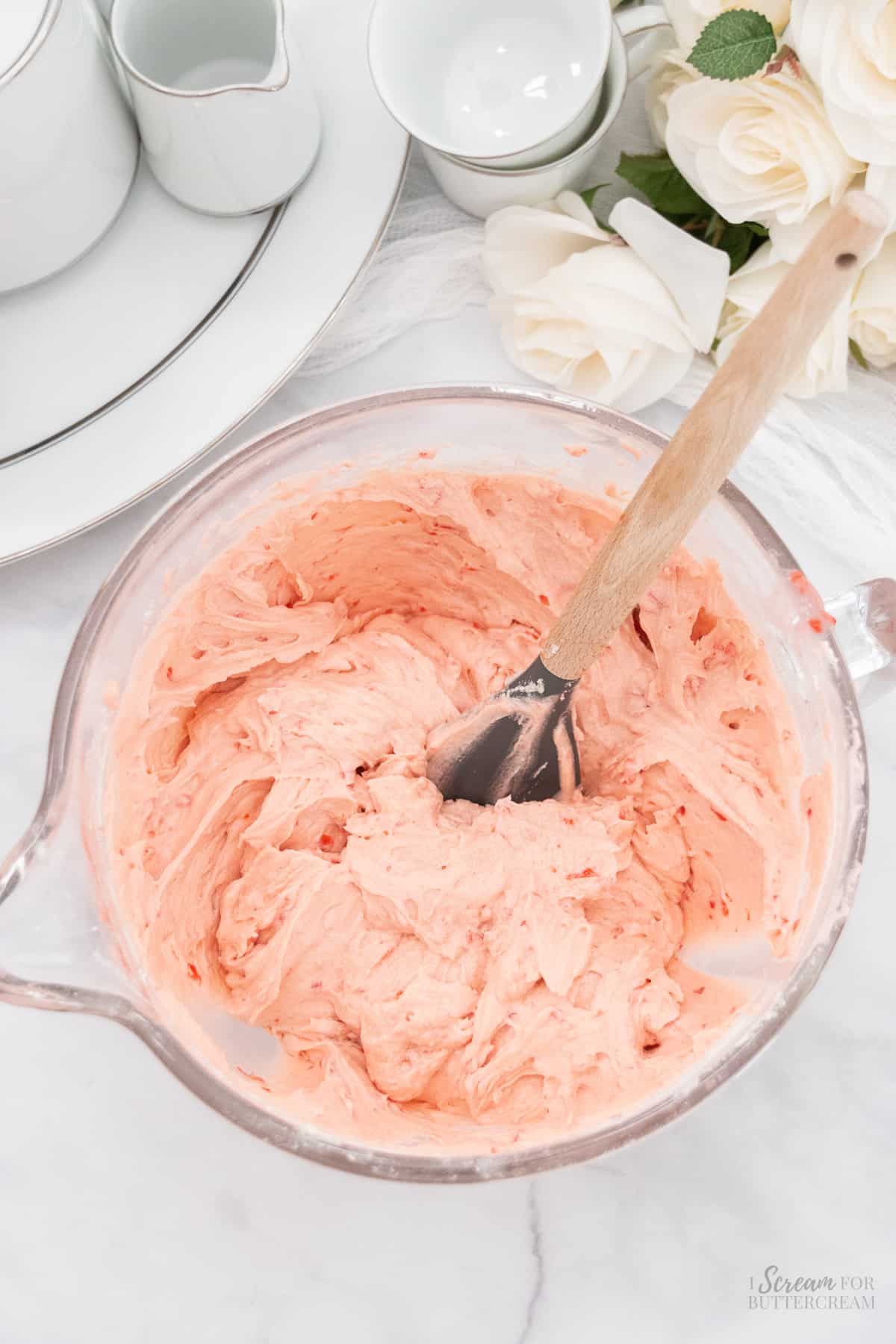 Cherry vanilla cake batter in a large glass mixing bowl with a spatula.