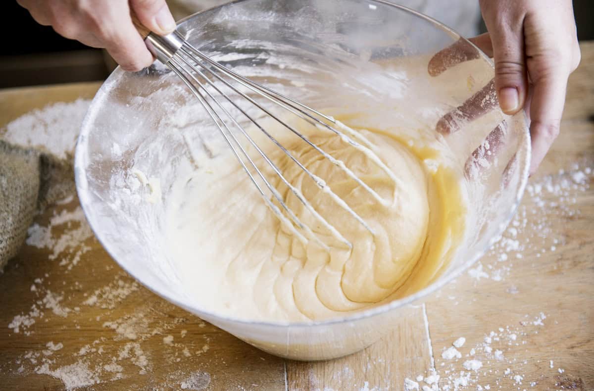 Cake batter in a glass bowl with a whisk.