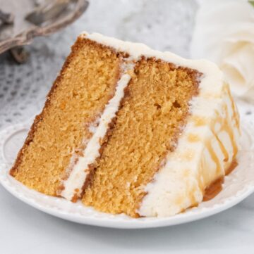 Close up of layer caramel cake slice on a white plate.